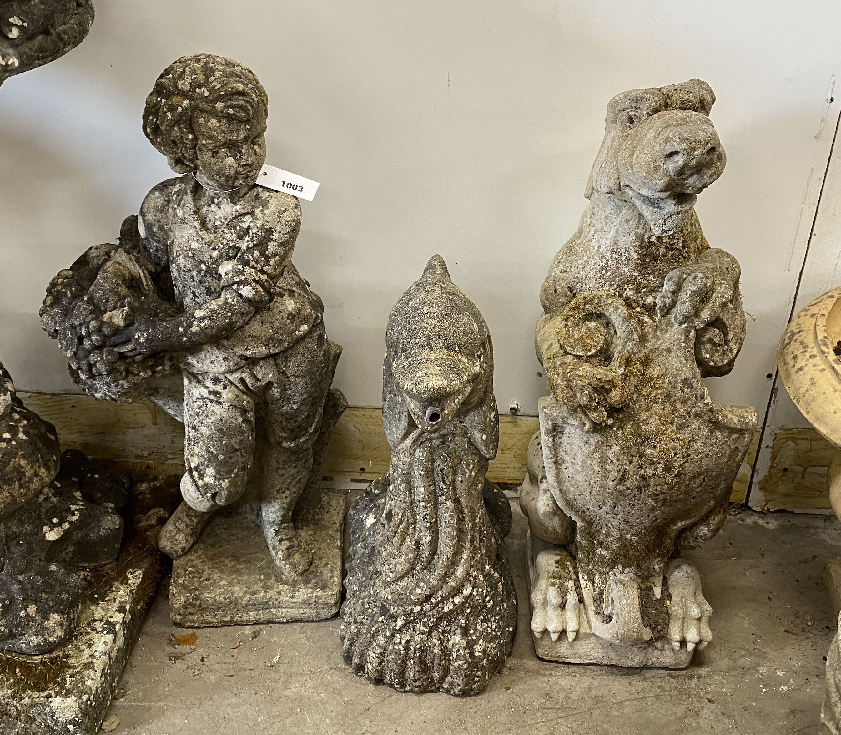 Three reconstituted stone garden ornaments, flower seller, dolphin and heraldic lion, largest height 72cm