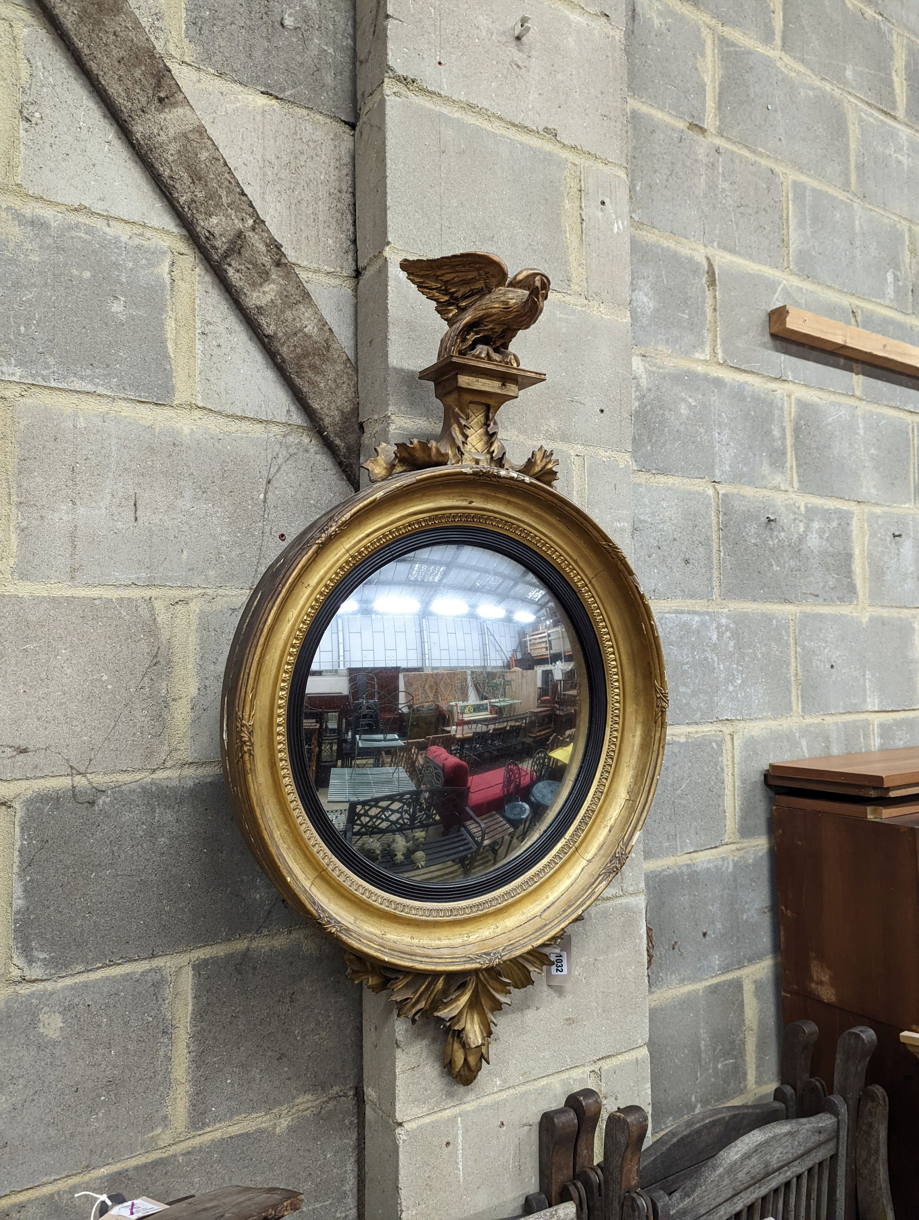 A Regency carved giltwood and gesso convex wall mirror, eagle surmount and ebonised slip, width 64cm, height 106cm