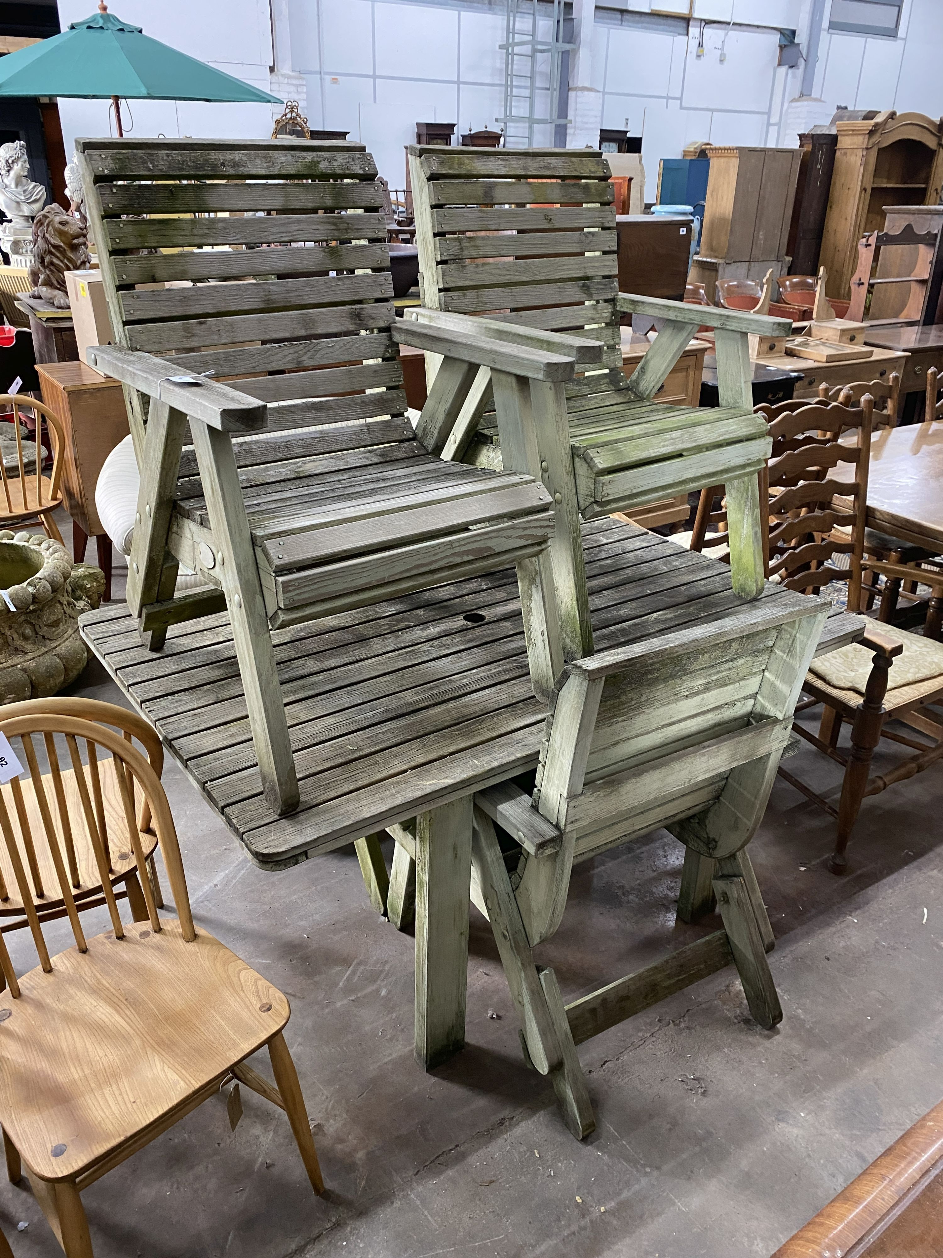 A weathered teak rectangular slatted garden table, length 145cm, depth 100cm, height 70cm and four weathered teak elbow chairs