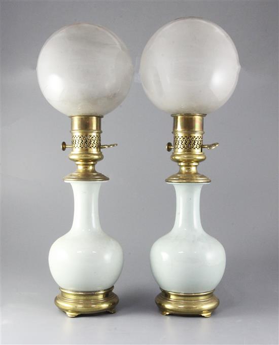 A pair of mid 19th century French ormolu mounted celadon porcelain oil lamps, with opaque circular glass shades, height 23in. A pair of mid 19th century French ormolu mounted celadon porcelain oil lamps, with opaque circular glass shades, height 23in.