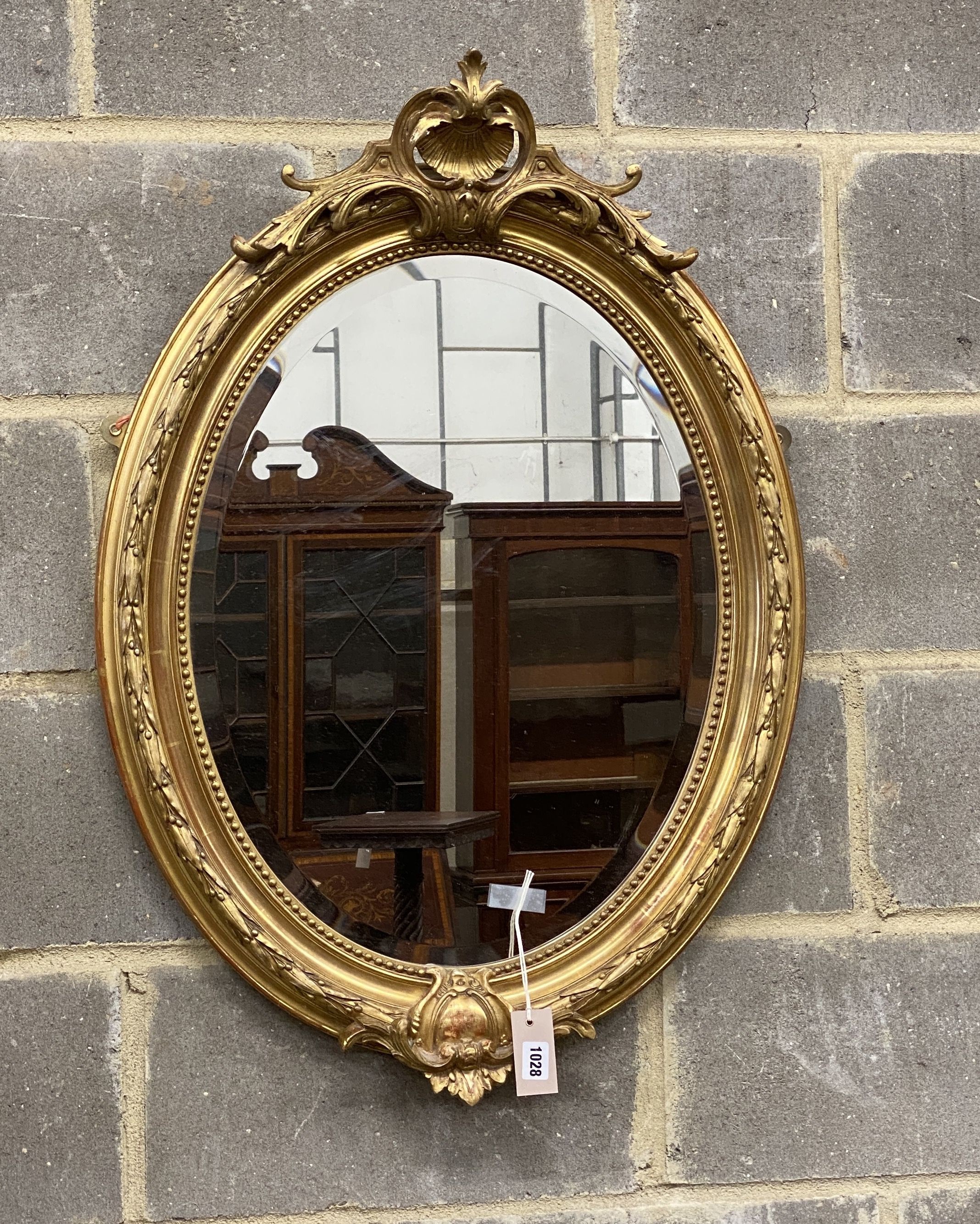 A Victorian style oval carved giltwood and gesso wall mirror, width 60cm, height 88cm