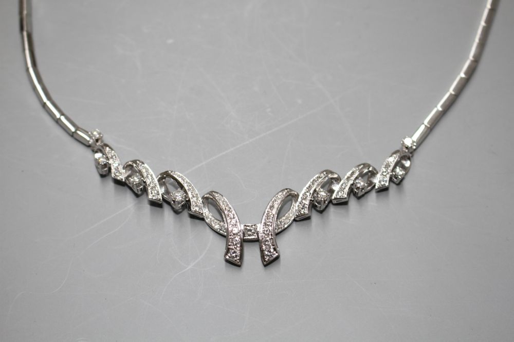 A modern 750 white metal and diamond set open scroll necklace,