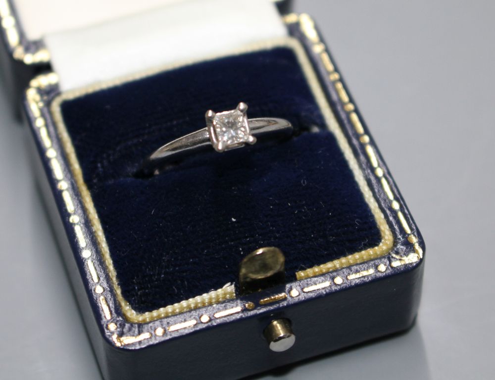 A modern 14k white metal and princess cut solitaire diamond ring, the stone weighing 0.25cts,