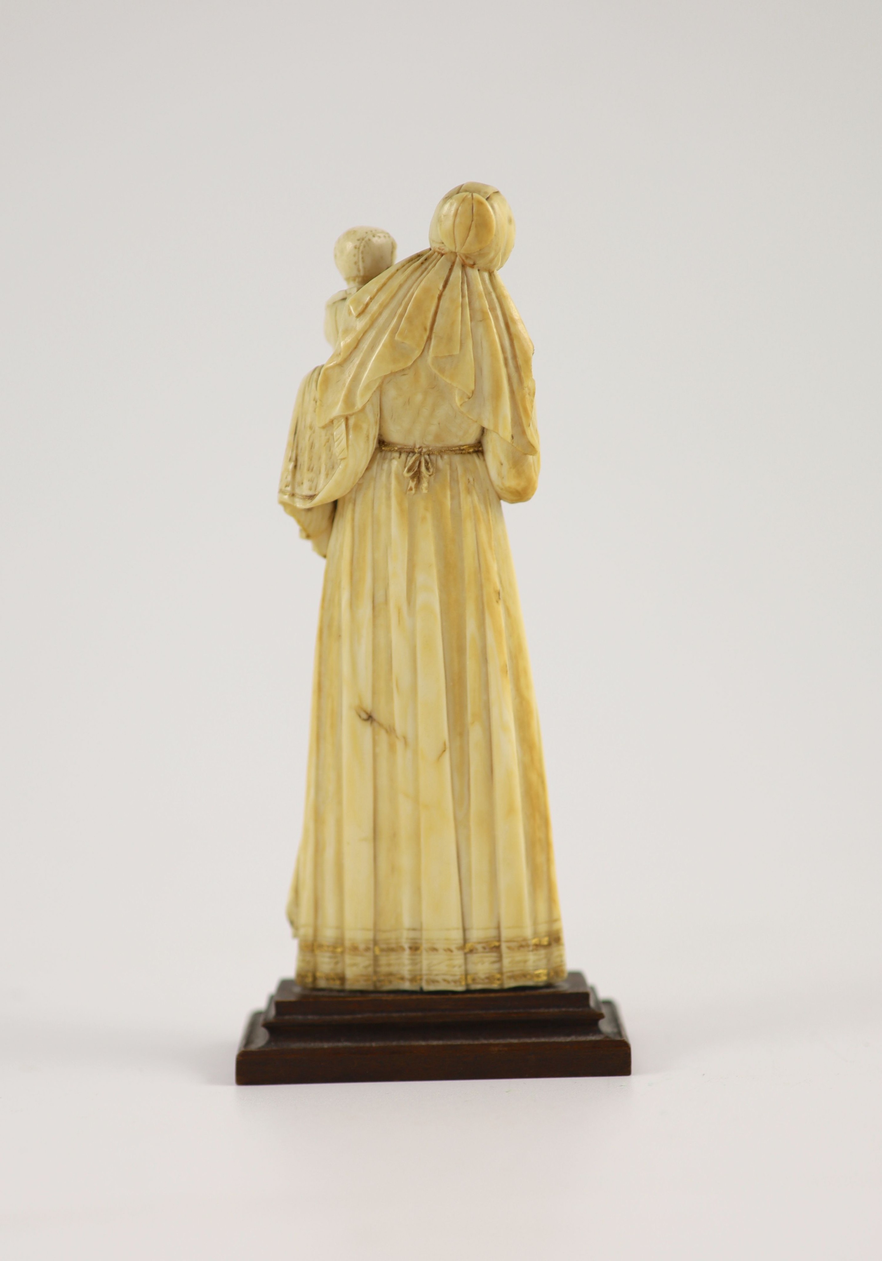 A 17th century French ivory group of a mother and child Height overall 14.5cm.