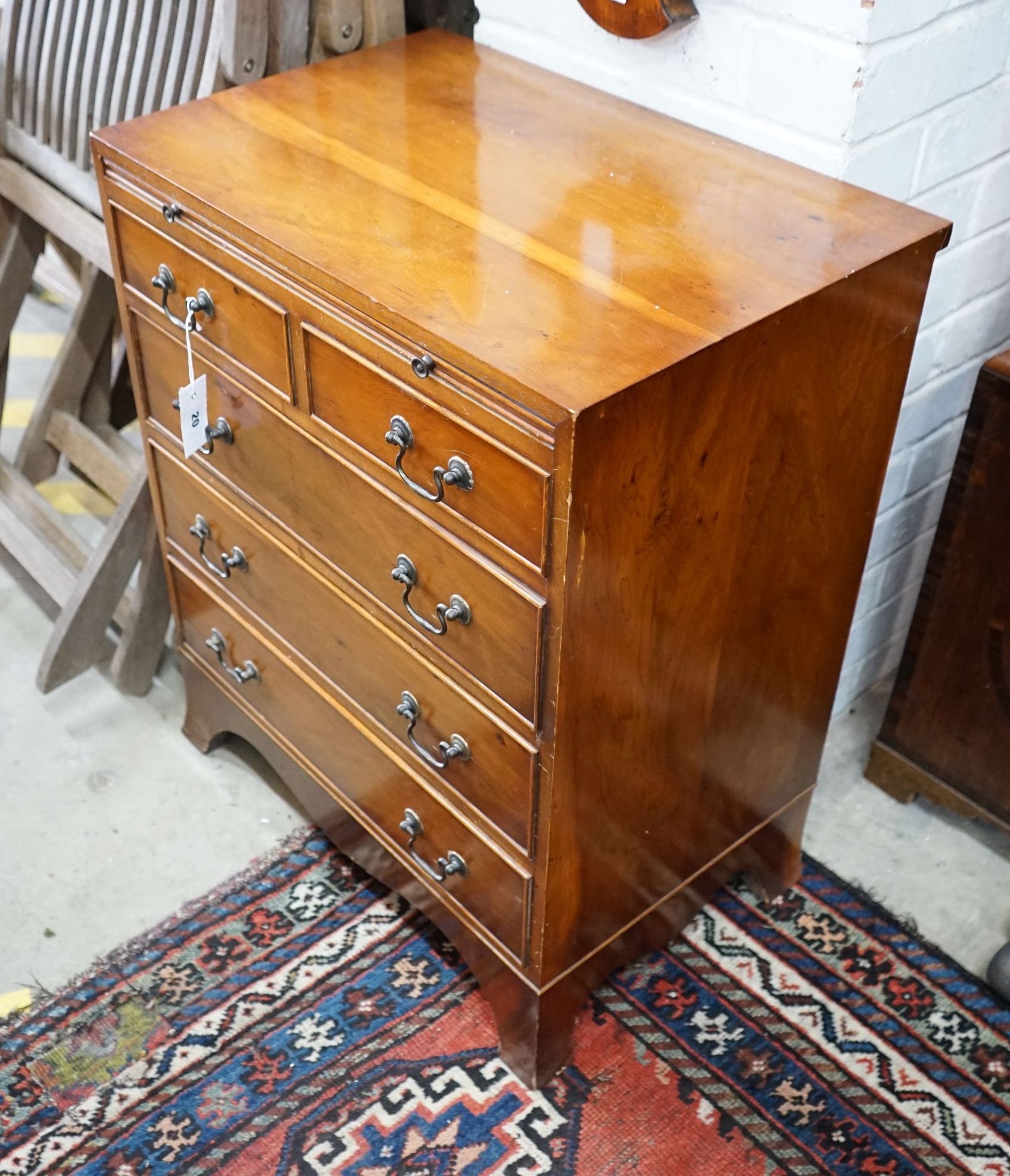 A small reproduction yew bachelor's chest of two short and three long drawers below brush slide, width 60cm, depth 40cm, height 74cm