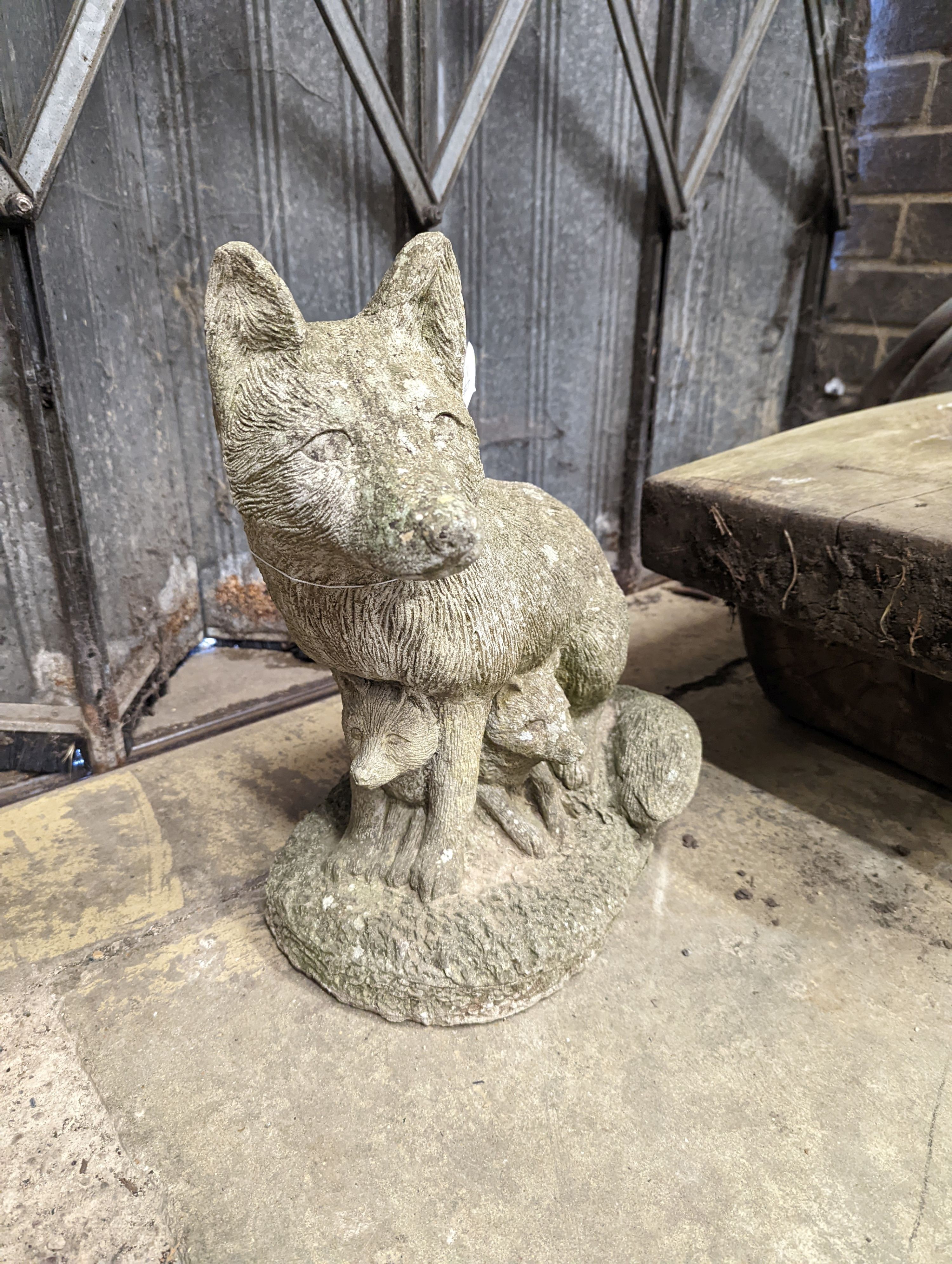 A reconstituted stone garden ornament modelled as a fox with cub, height 42cm