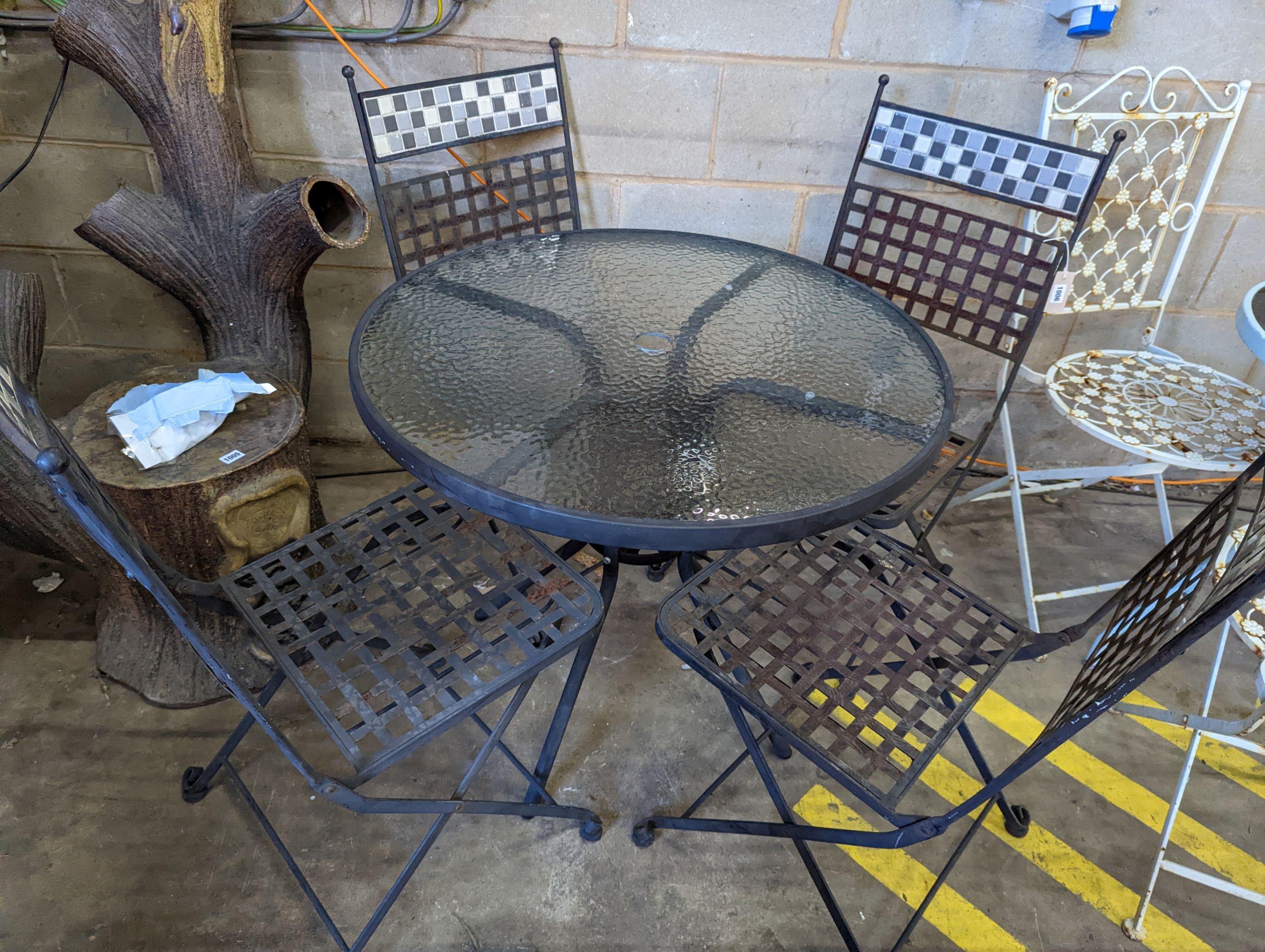 A circular glass top garden table, diameter 80cm, height 71cm and four metal folding garden chairs