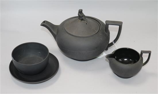 A black basalt teapot, a cream jug, a saucer and a bowl A black basalt teapot, a cream jug, a saucer and a bowl