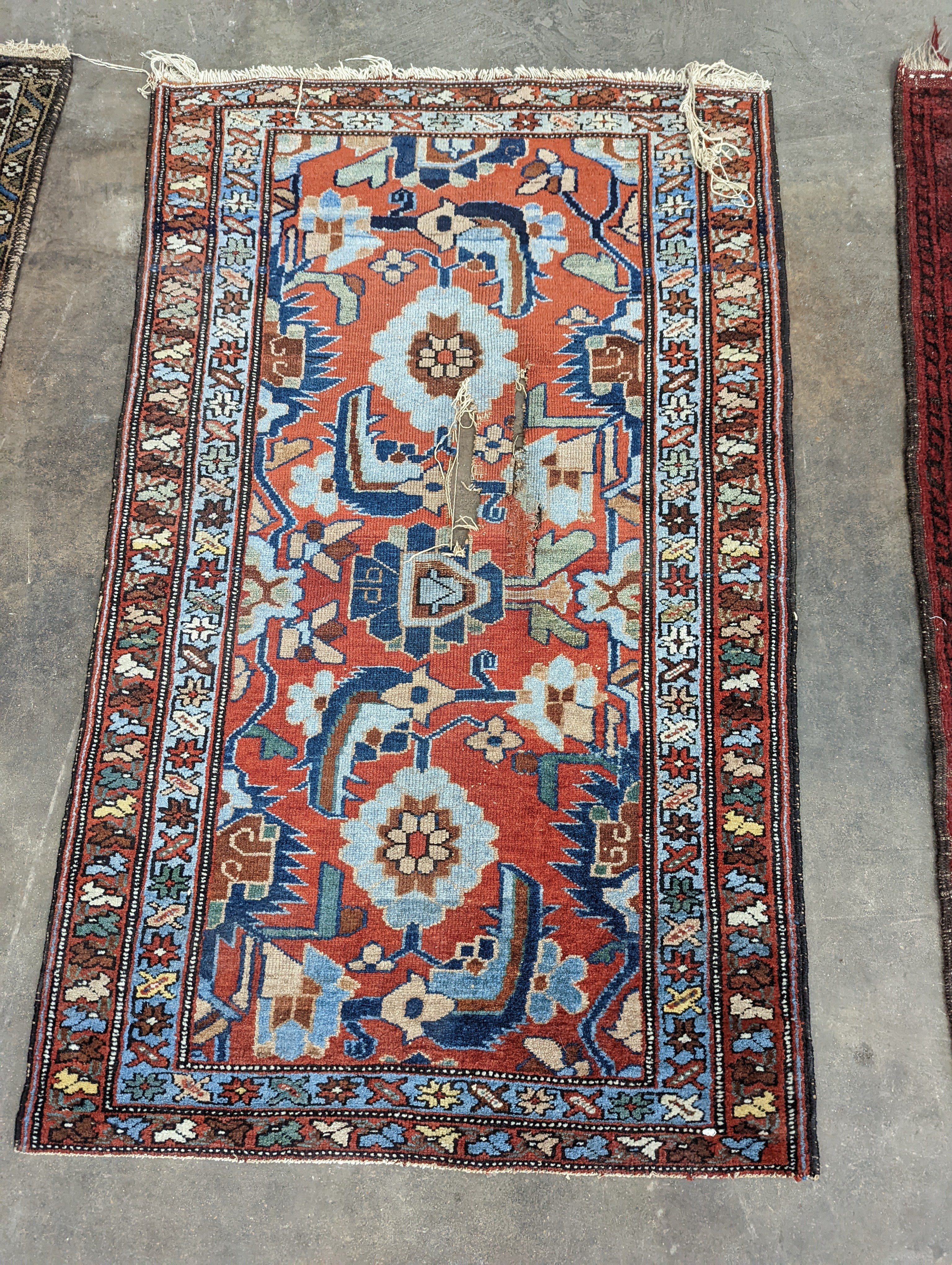A Persian red ground rug, woven with stylised foliage, 126 x 74cm