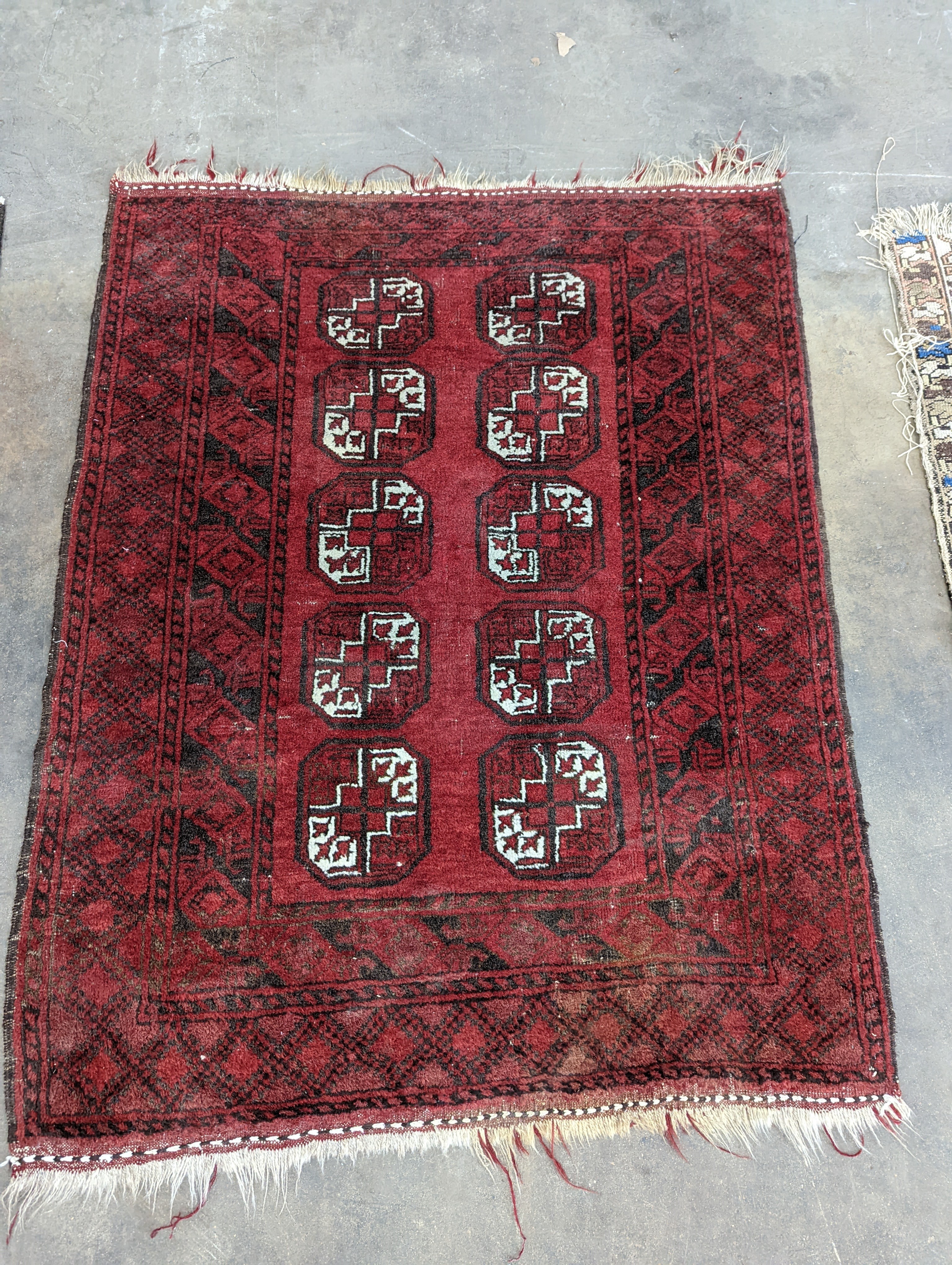 An Afghan red ground rug, woven with two rows of elephant feet, 130 x 100cm