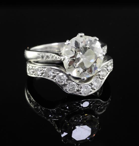 A modern platinum and diamond wedding set comprising a single stone diamond ring and eleven stone diamond set shaped band, size S.