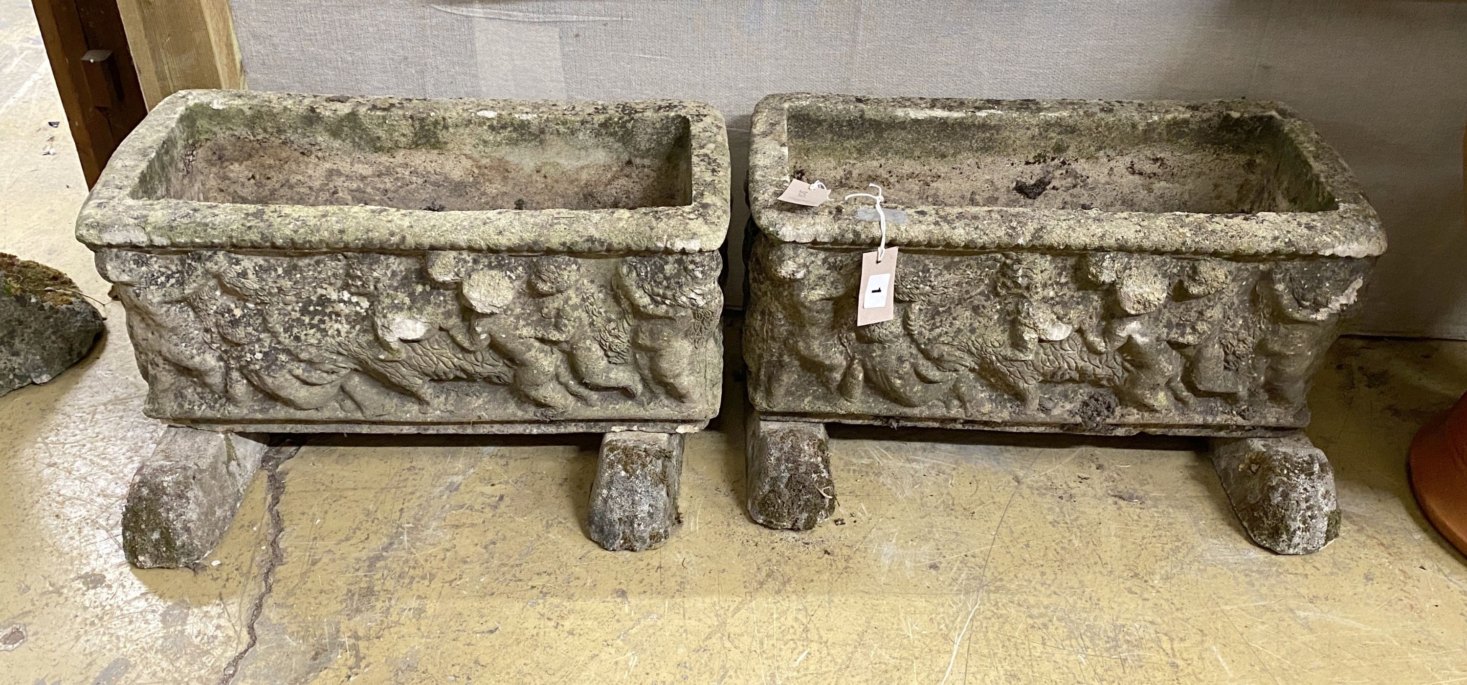 A pair of rectangular reconstituted stone garden planters on stands moulded with cherubs, width 54cm, depth 25cm, height 29cm