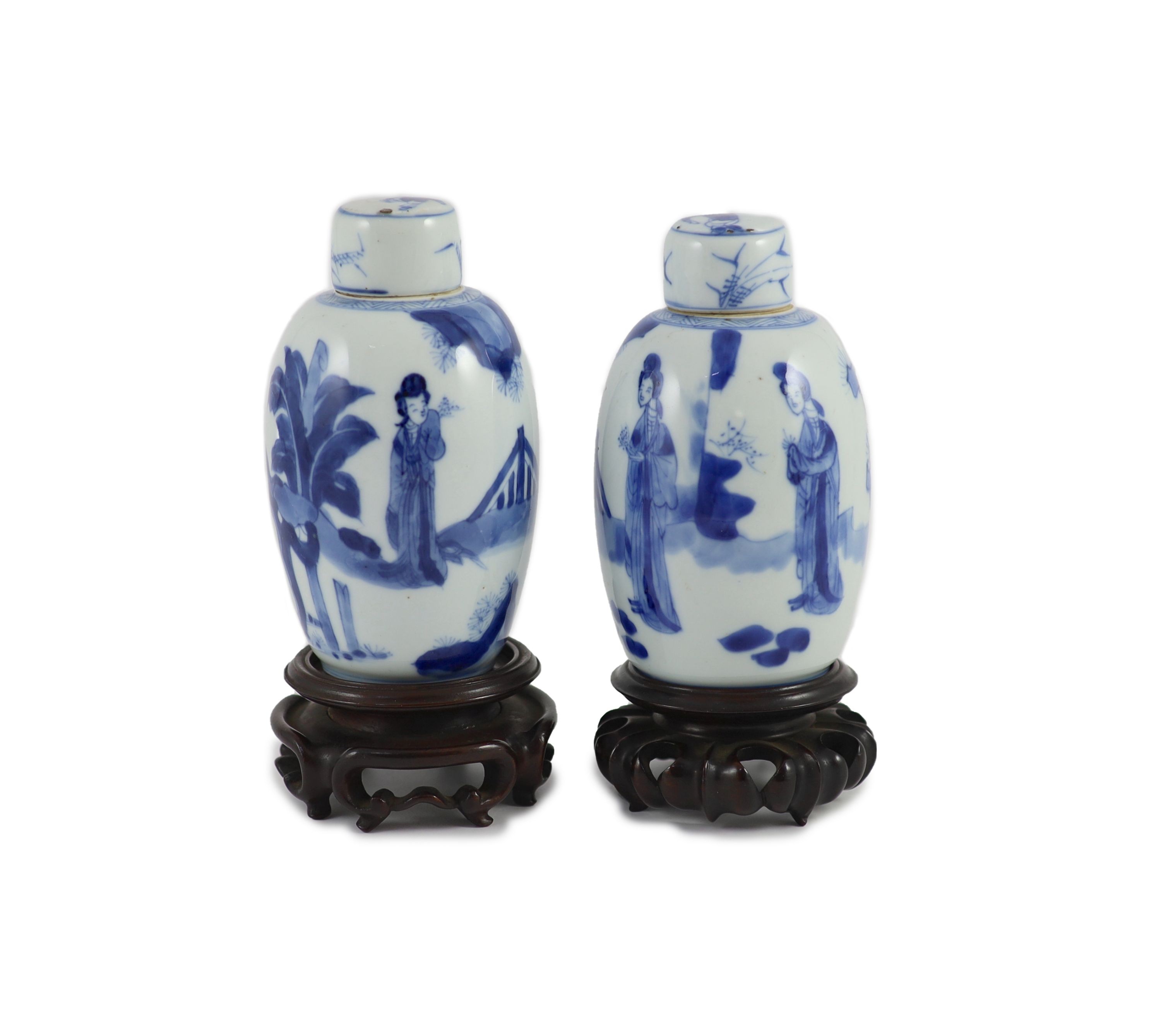 A pair of Chinese blue and white ovoid jars and covers, Kangxi period, 13.2 and 13.5 cm high, wood stands