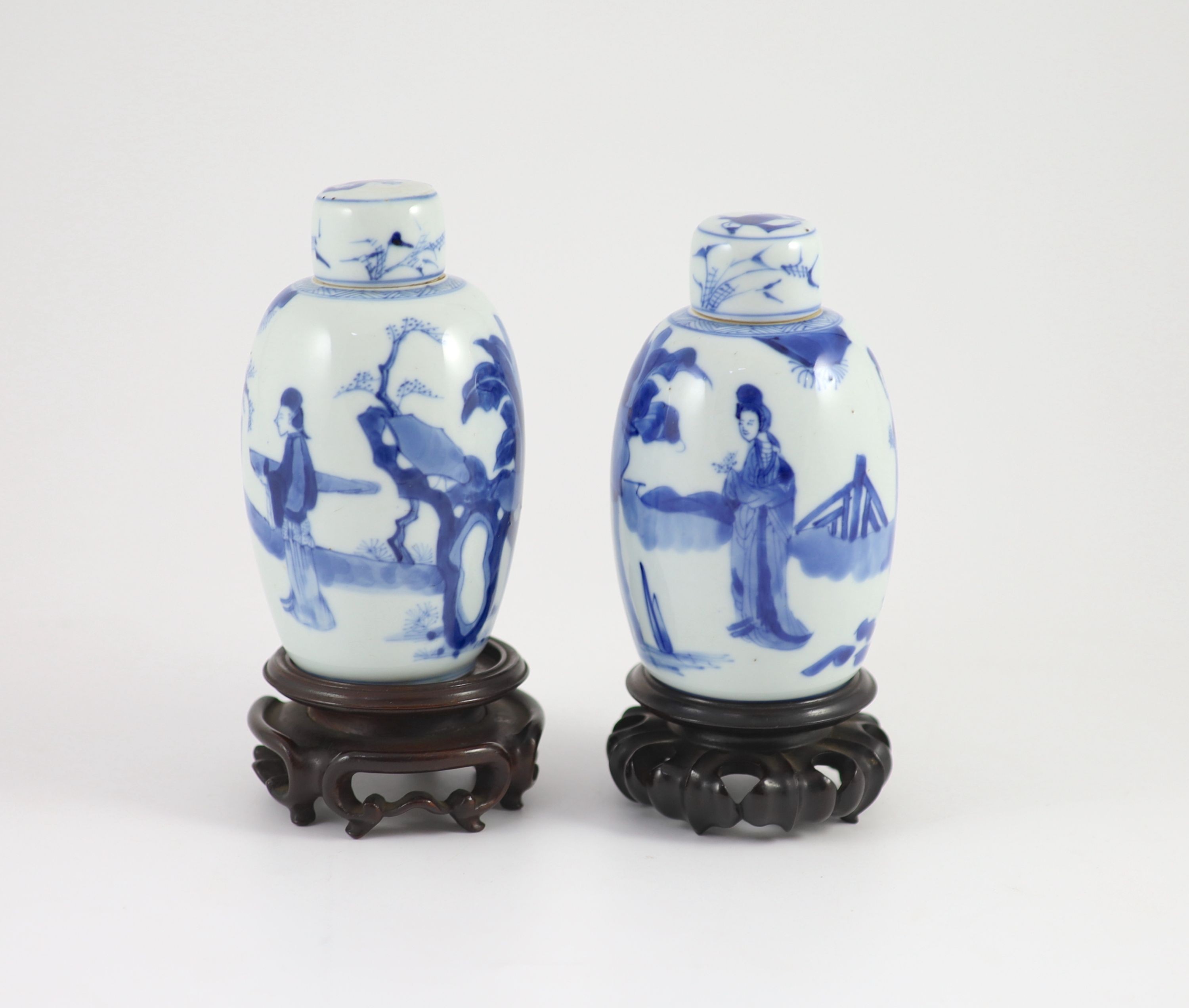 A pair of Chinese blue and white ovoid jars and covers, Kangxi period, 13.2 and 13.5 cm high, wood stands