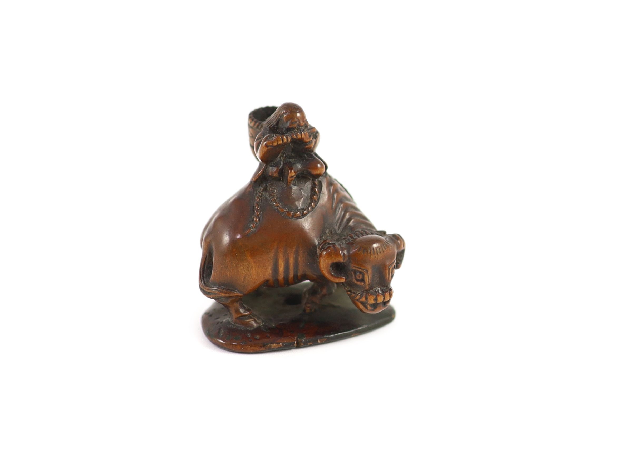 A Japanese boxwood netsuke of Semimaru playing the flute and riding upon an ox, School of Tomotada, early 19th century, 4cm high