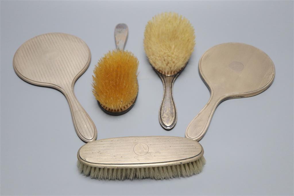 Two late 1920s silver mounted hand mirrors and three silver mounted brushes.