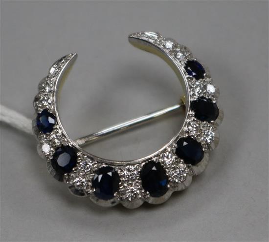 A modern 18ct gold, sapphire and diamond set crescent brooch, 28mm. A modern 18ct gold, sapphire and diamond set crescent brooch, 28mm.