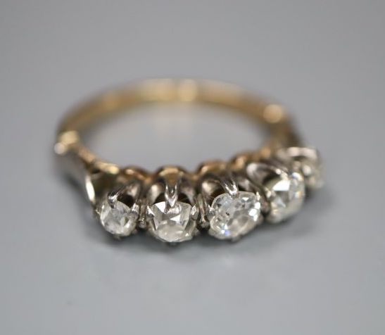 A yellow metal and graduated five stone diamond set half hoop ring, size H, gross 2.9 grams.