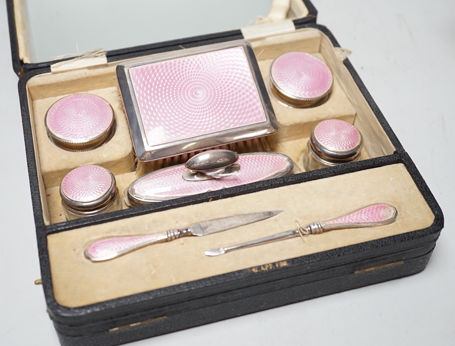 A cased George V nine piece silver and pink enamel mounted manicure set.                                                                                                                                                    