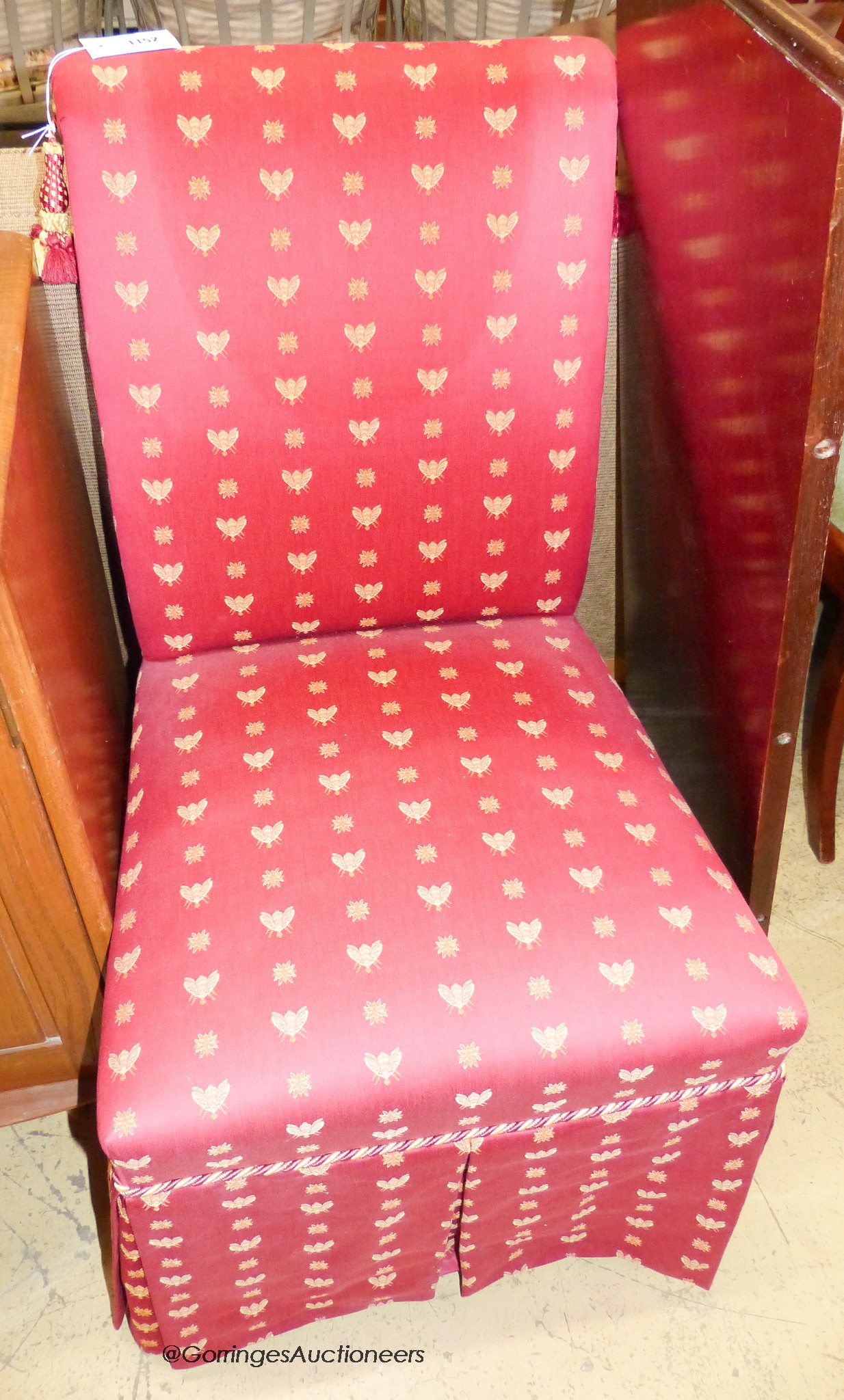 A side chair upholstered in bee patterned crimson fabric.                                                                                                                                                                   