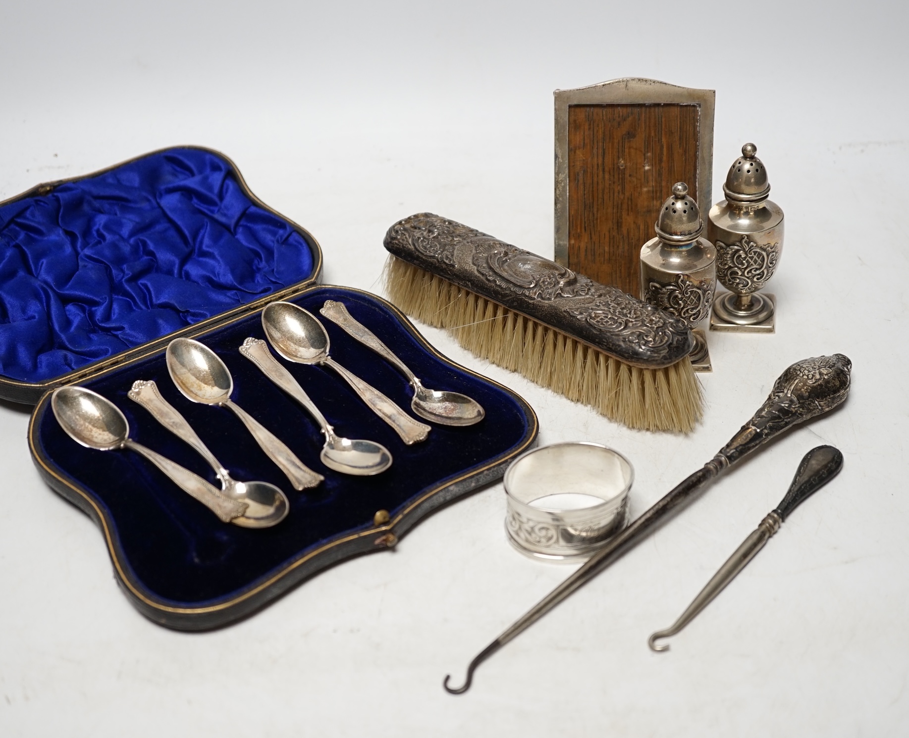 A cased set of six silver teaspoons, a pair of silver pepperettes and four other items including a photograph frame. Condition - poor to fair                                                                               