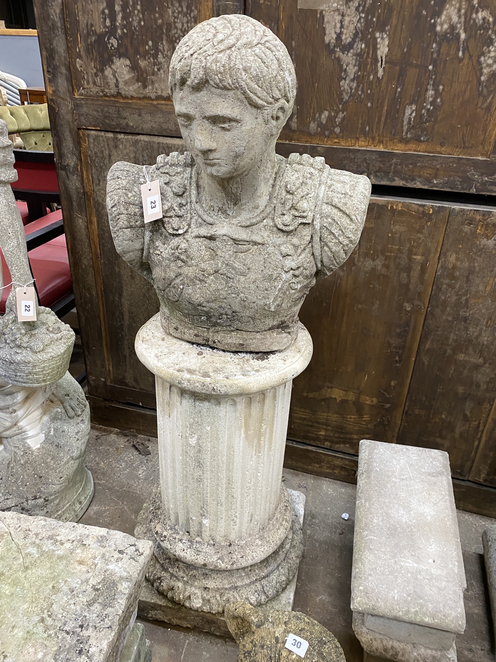 A reconstituted stone bust of a Roman warrior, on circular fluted plinth, height 123cm                                                                                                                                      