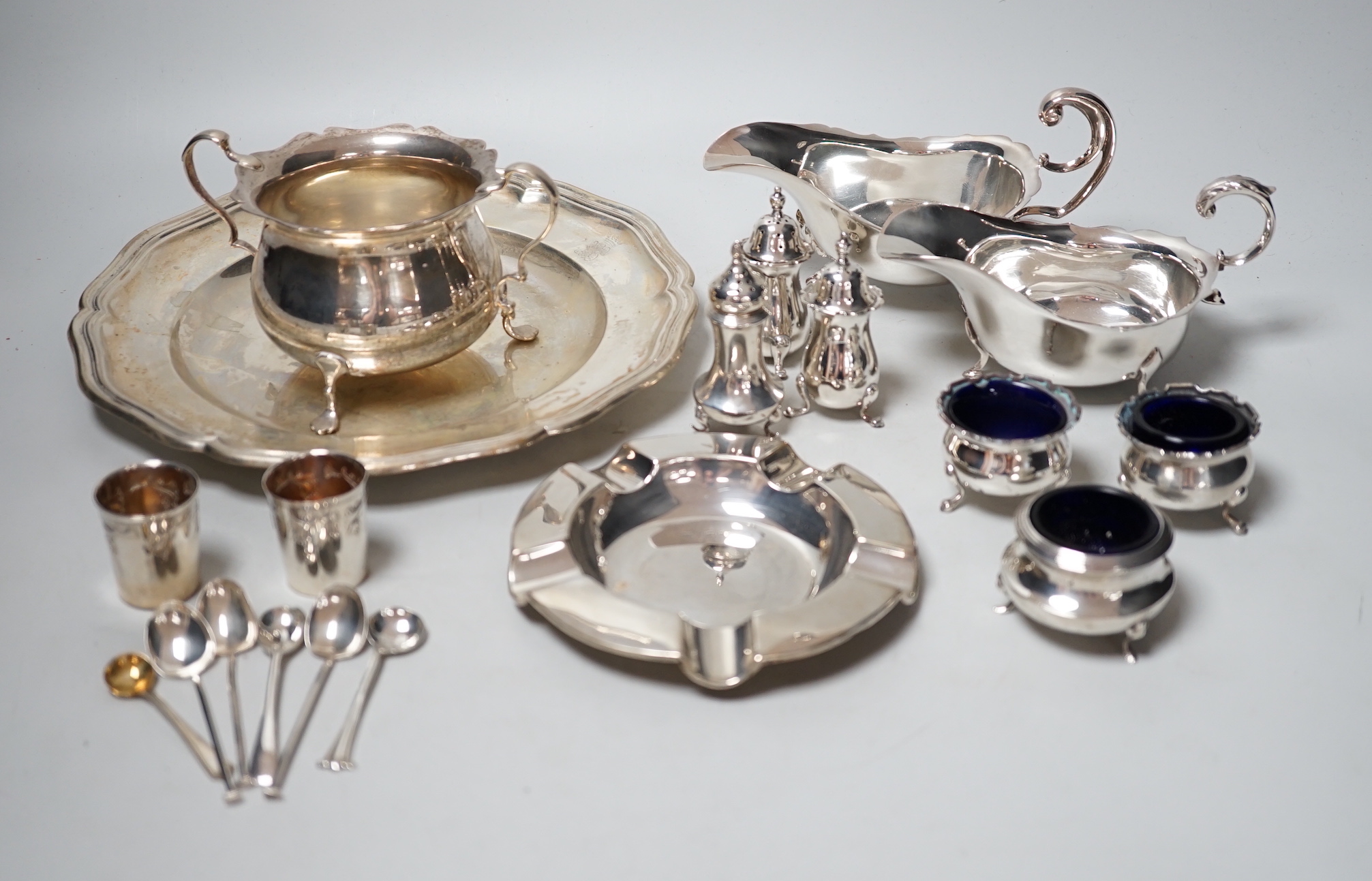 An 800 white metal plate, 24.8cm, a George V silver two handled bowl, a silver ashtray, six silver condiments, two 800 tots and minor plated ware, 24.1oz.                                                                  