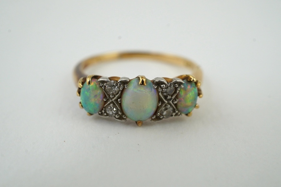 A yellow metal (stamped 18) and three stone white opal set half hoop ring, with diamond chip spacers, size M, gross weight 3.1 grams. Condition - poor to fair                                                              