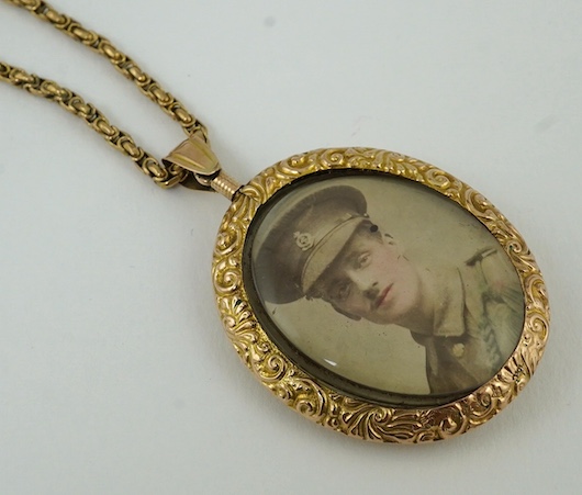 A George V embossed 9ct gold double portrait pendant, 44mm, on a 9ct chain, 37cm, gross weight 30.8 grams. Condition - poor to fair                                                                                         