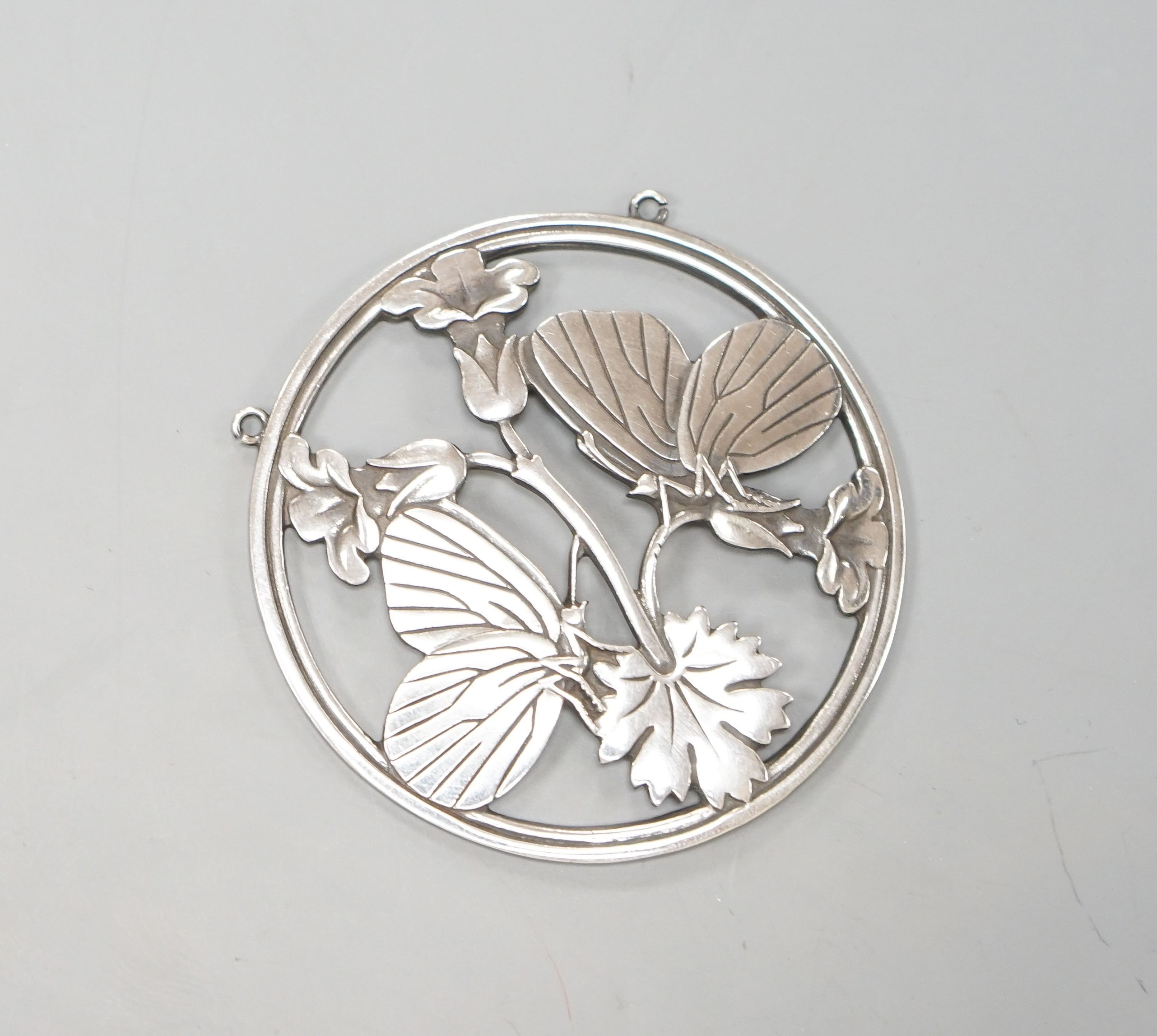 A Georg Jensen sterling circular 'two butterflies on flower' pendant, designed by Arno Malinowski, no. 105, 52mm.                                                                                                           
