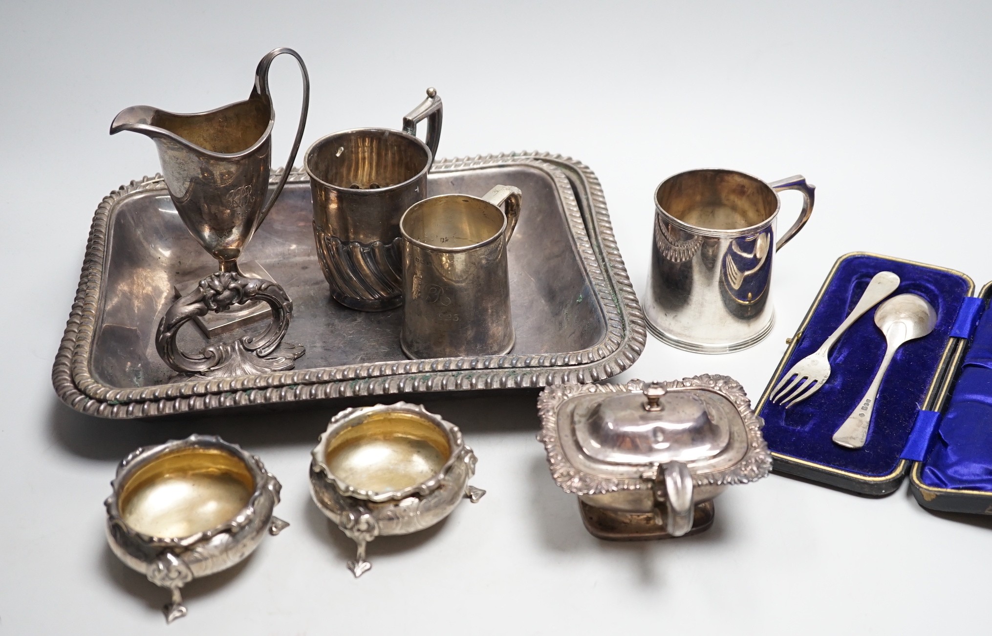 A small collection of English silver to include a pair of Victorian cauldron salts, two small beakers, a cream jug with presentation script, a George IV silver mustard pot with hinged cover, London, 1823 and a boxed chri