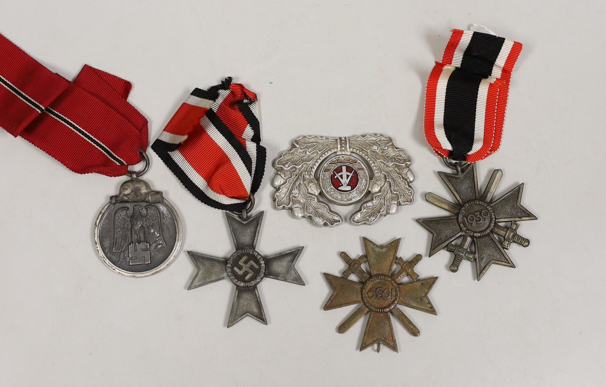 Four German Third Reich medals, comprising three merit crosses, and a Winterschlacht medal, together with a Russian cap badge.                                                                                              
