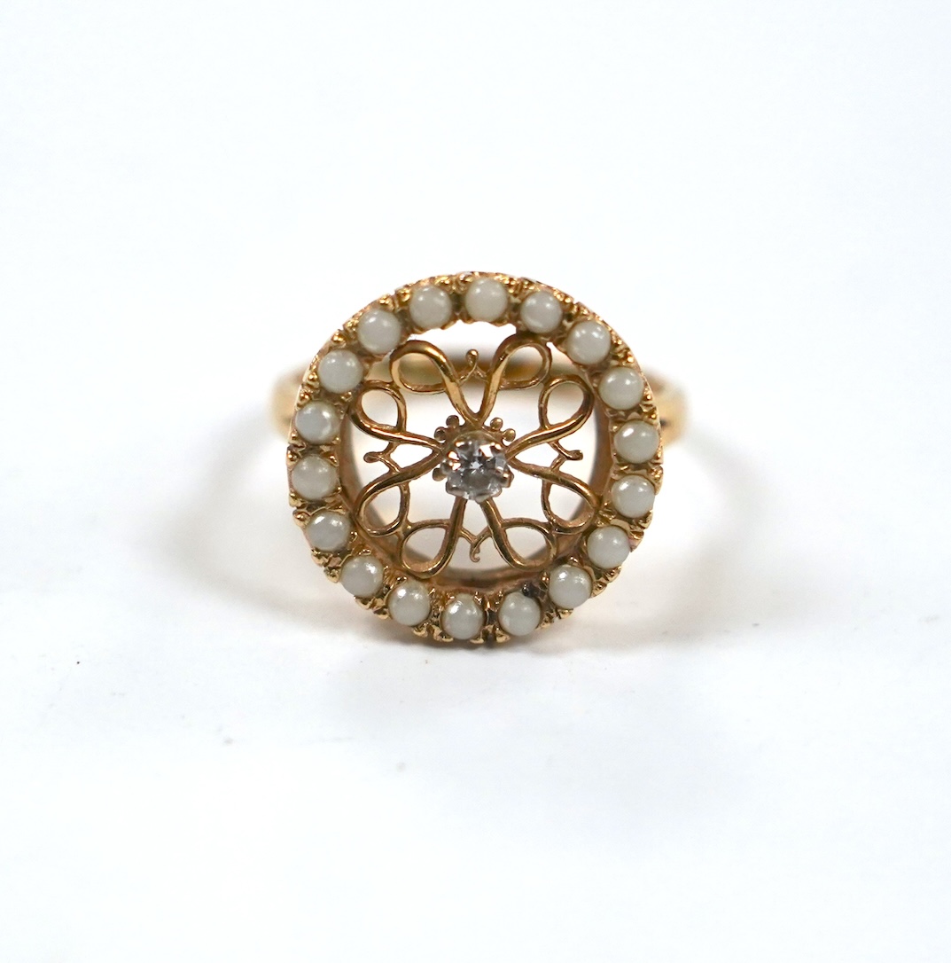 A pierced 14k yellow metal, seed pearl and diamond cluster set circular ring, size P/Q, gross weight 5.2 grams.                                                                                                             