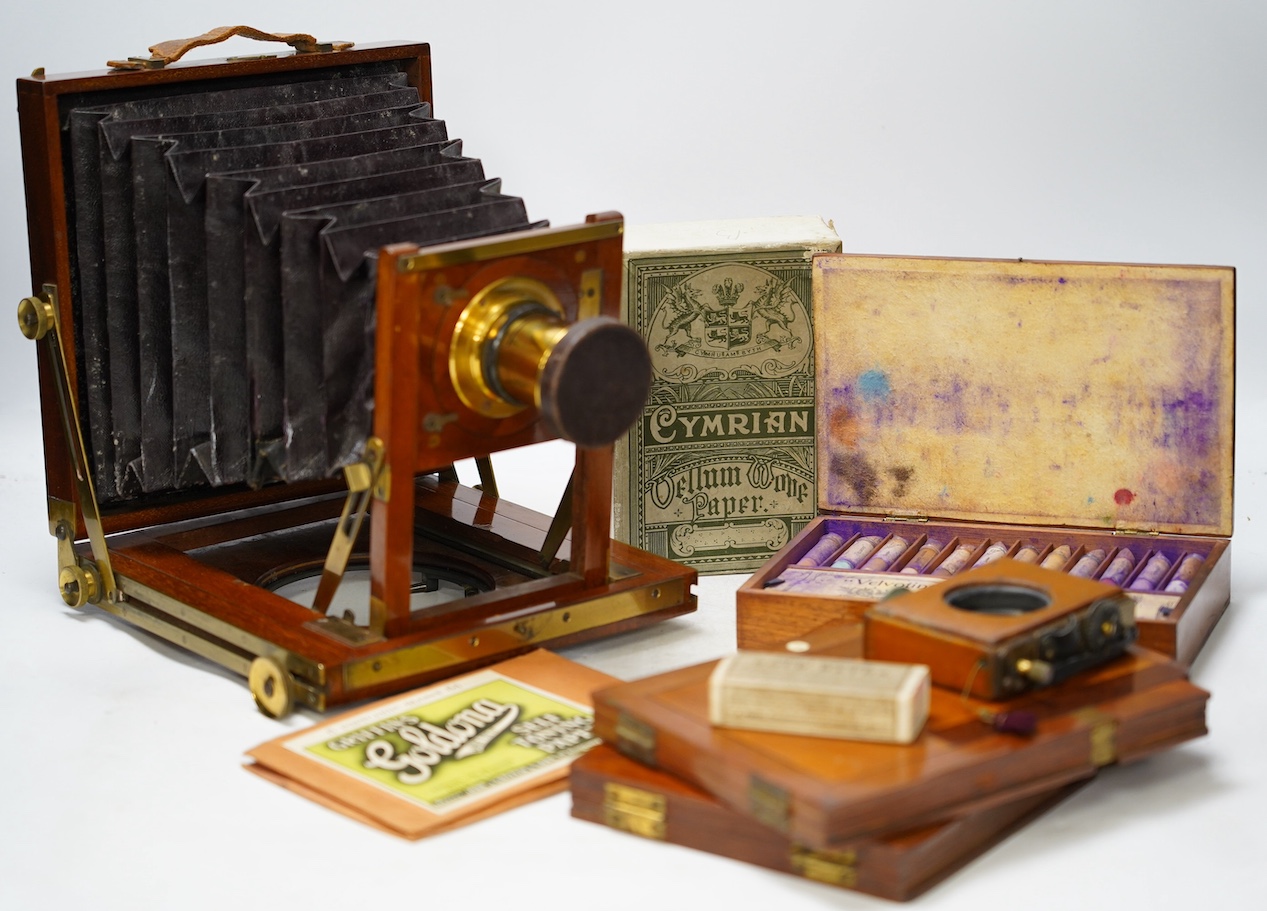 A late 19th century brass and mahogany half plate bellows camera with oak tripod stand and a lens engraved ‘ERR 6.5 x 4.75’, together with a good quantity of contemporary accessories including a shutter action, ten negat