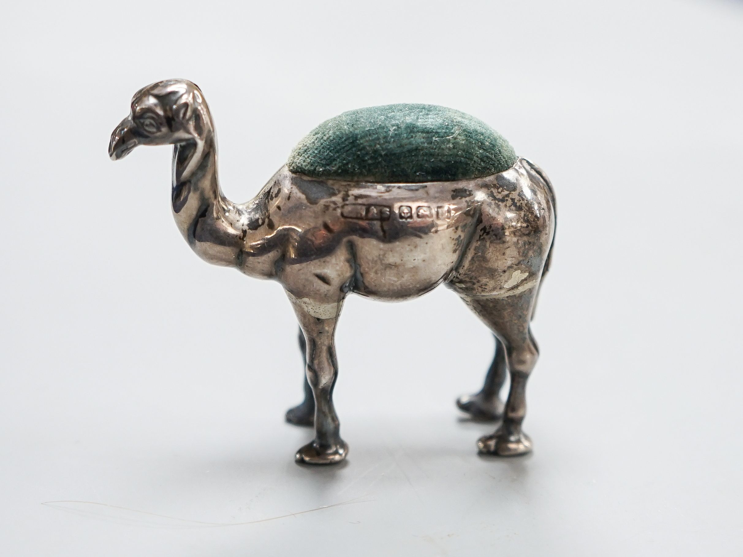 A George V novelty silver mounted pin cushion, modelled as a camel, ?H &S, Birmingham, 1911, height 49mm(a.f).                                                                                                              