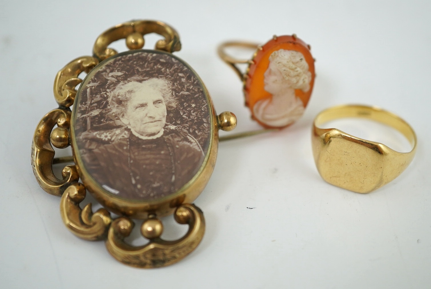 A yellow metal signet ring, stamped 18ct., 5.1 g, a cameo ring, indistinct Mark, 4.46 g gross and a reversible brooch. Condition - incomplete otherwise fair                                                                