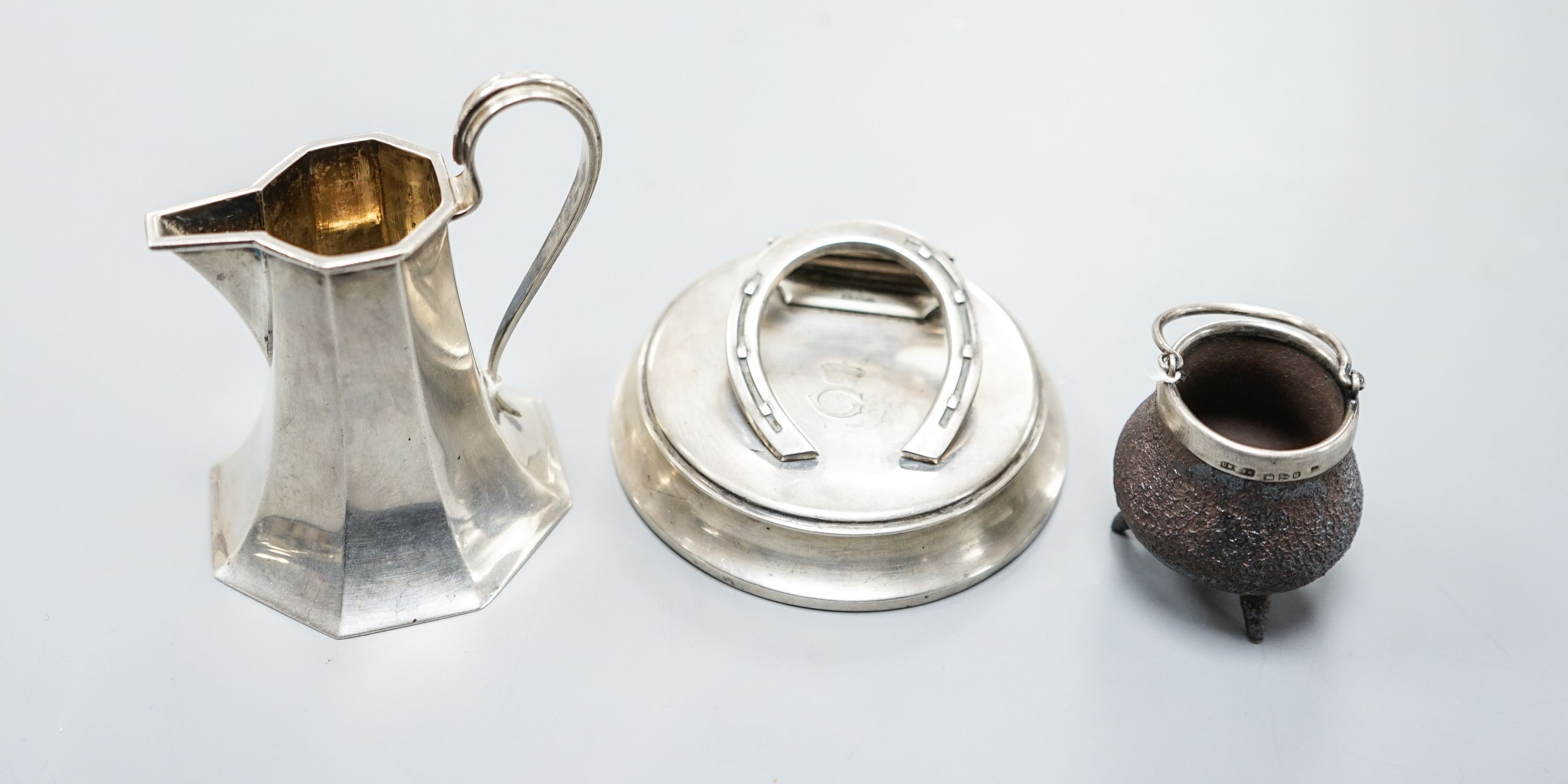 An Edwardian silver horseshoe letter clip, London, 1907, 86mm, a silver cream jug and a silver mounted Doulton Lambeth stoneware miniature cauldron.                                                                        