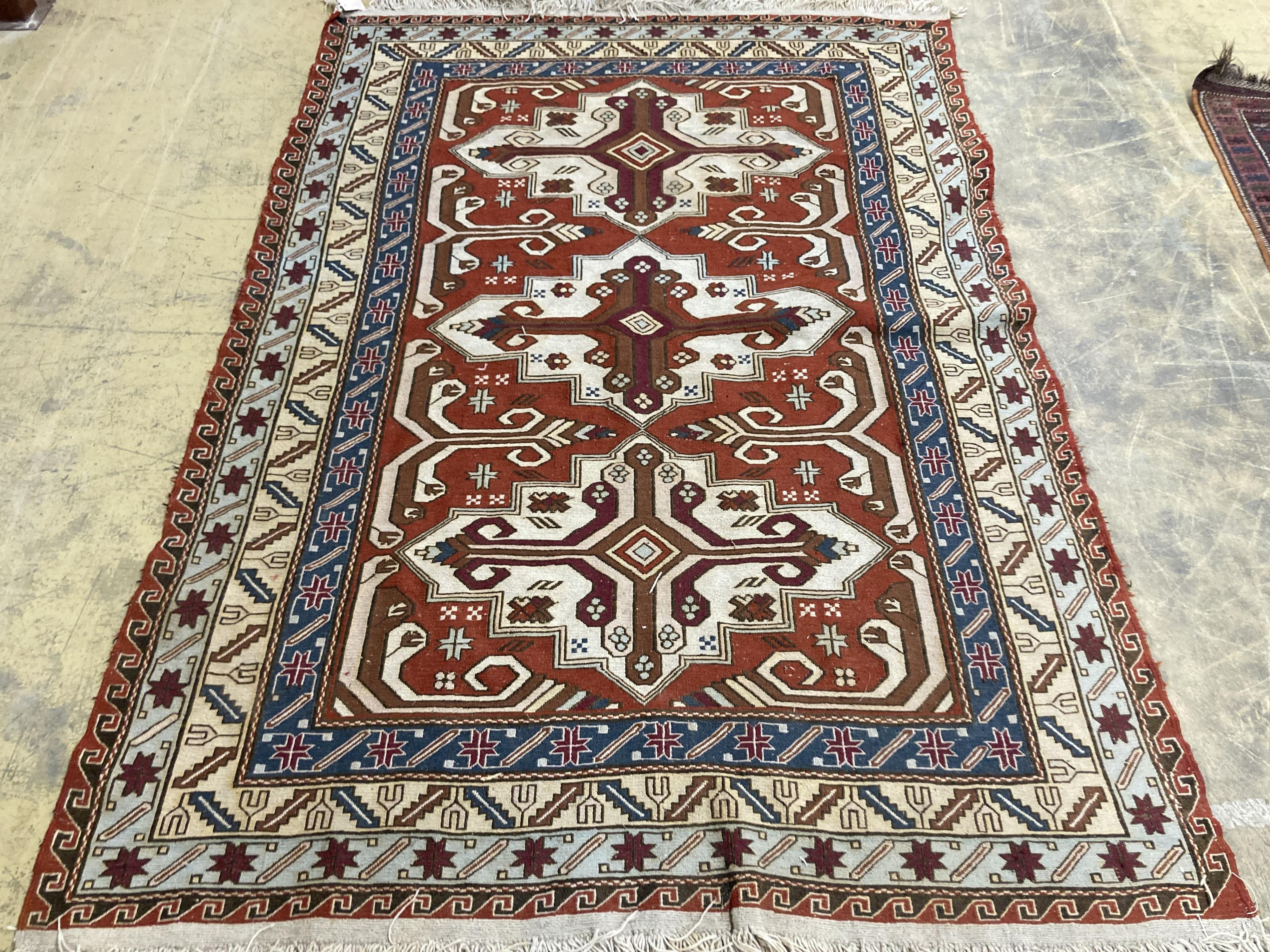 A Caucasian design red ground rug, 240 x 165 cms.                                                                                                                                                                           
