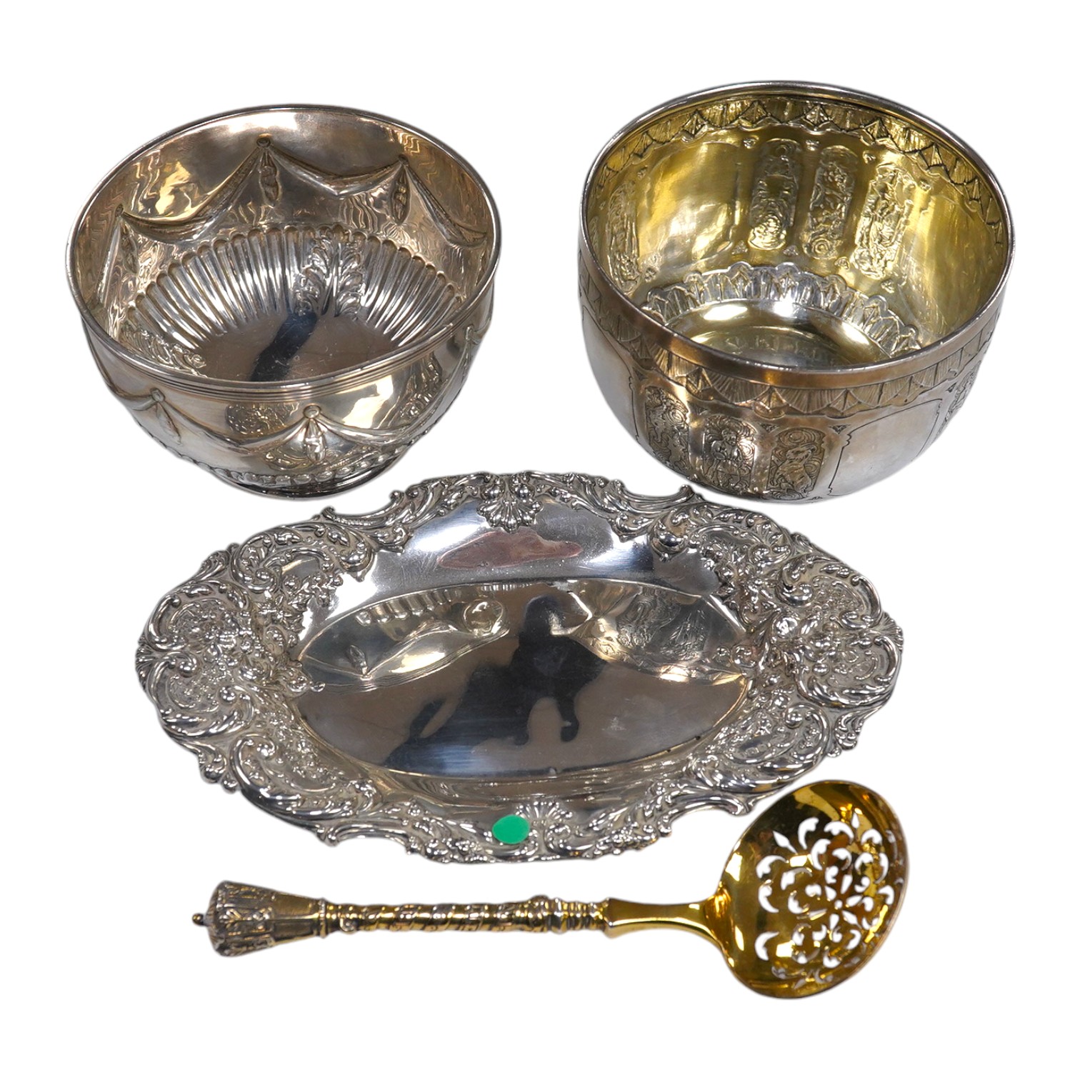 Two Victorian silver sugar bowls, a Victorian silver gilt sifter ladle and a repousse silver dish, 11.8oz. Condition - fair to good                                                                                         