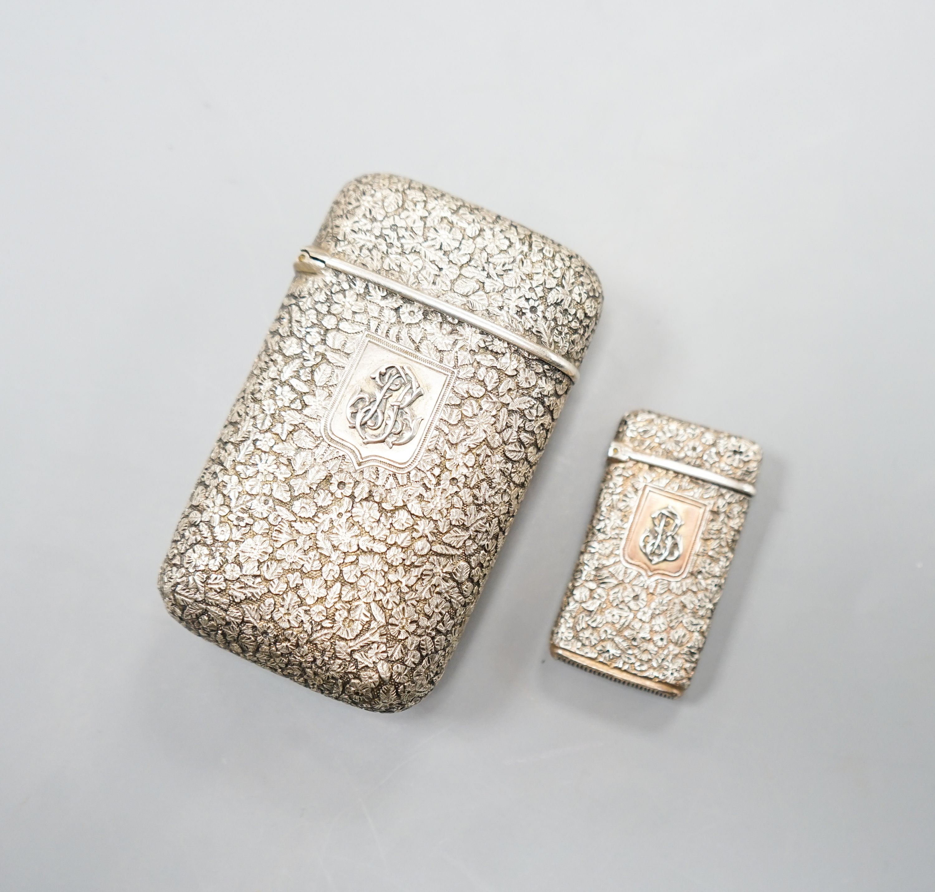 A late 19th century French embossed white metal cigarette case, 76mm, with monogram applique and a similar vesta case.                                                                                                      