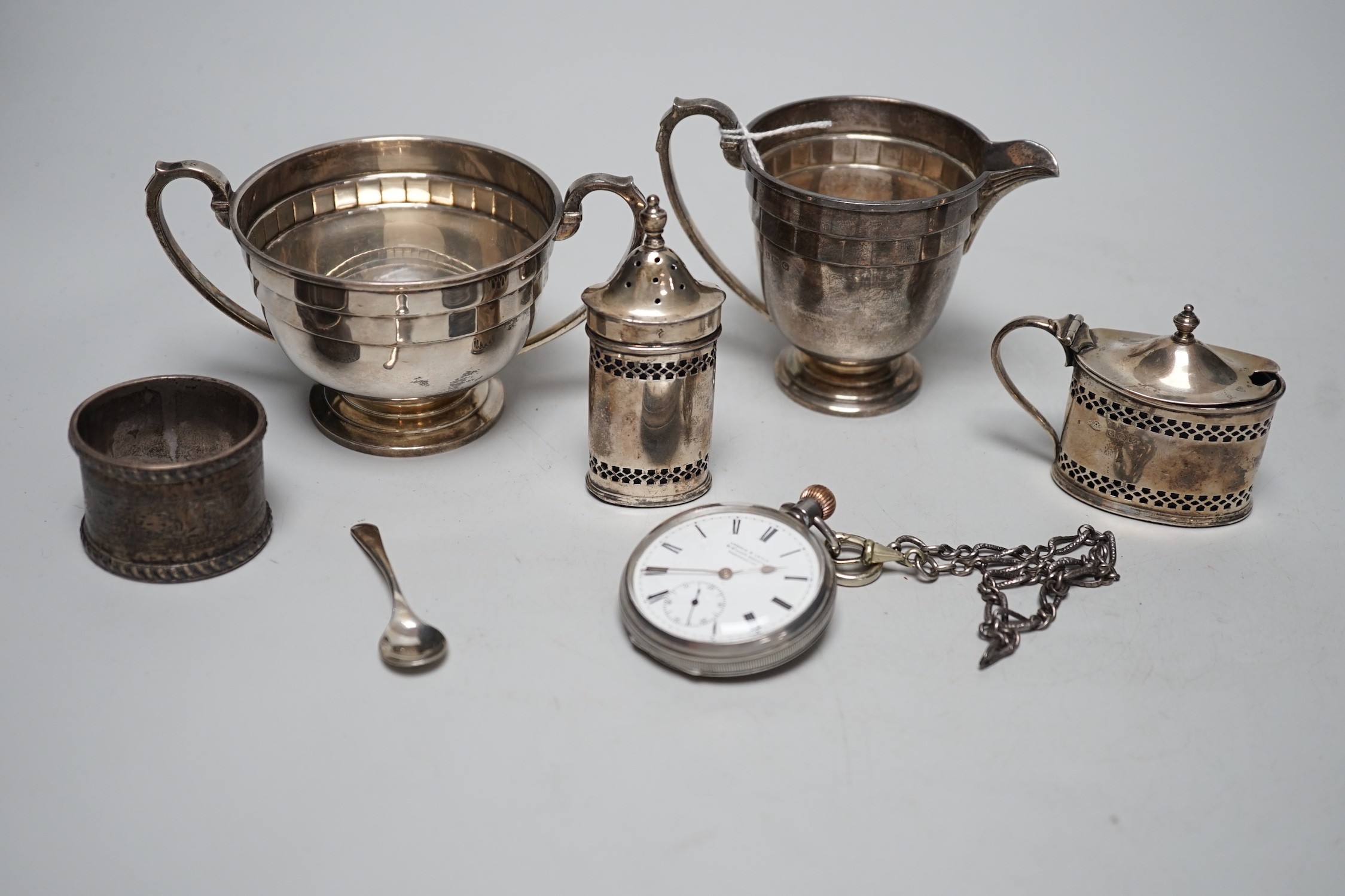 Small silverware, including a George V cream jug and matching sugar bowl, a mustard pot and matching pepper pot, silver serviette ring and a gentleman’s silver pocket watch and chain.                                     
