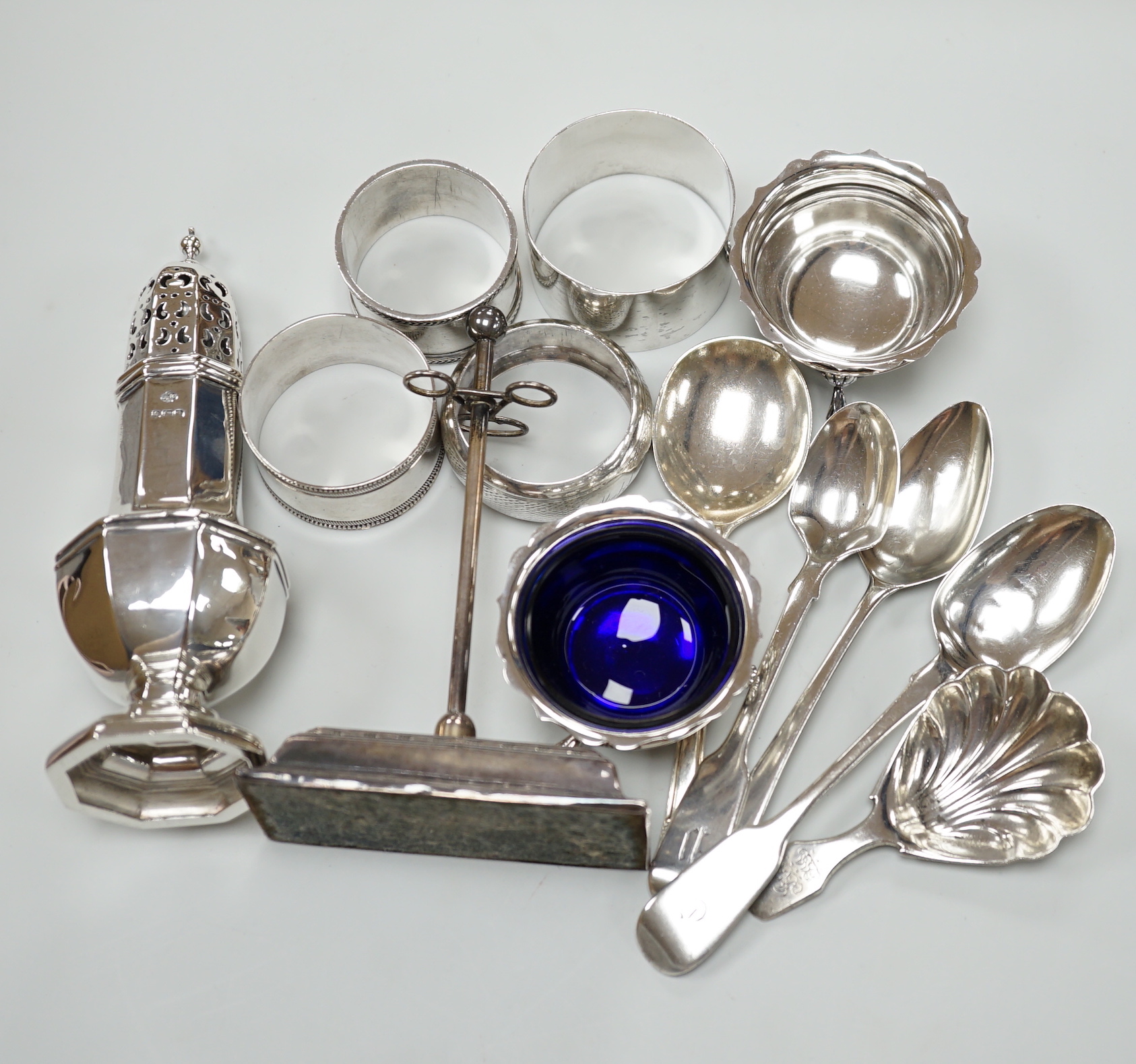 Sundry small silver including a George V pepperette, four silver napkin rings, a silver mounted implement stand, pair of salts (liner missing), four silver spoons and a George IV caddy spoon.                             