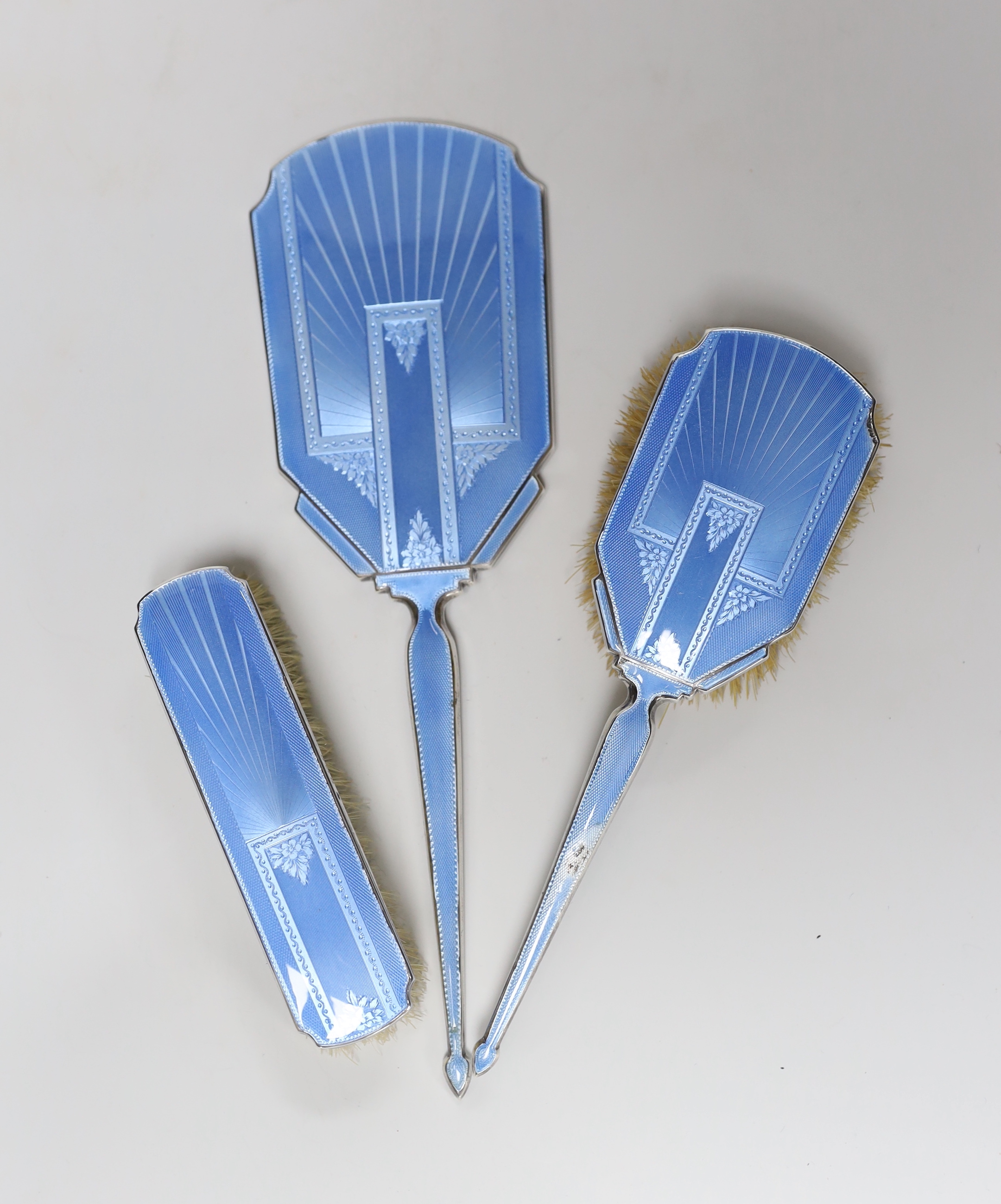 A George V Art Deco silver and blue guilloche enamel mounted three piece mirror and brush set, C.S. Green & Co, Birmingham, 1933, mirror 29.6cm.                                                                            