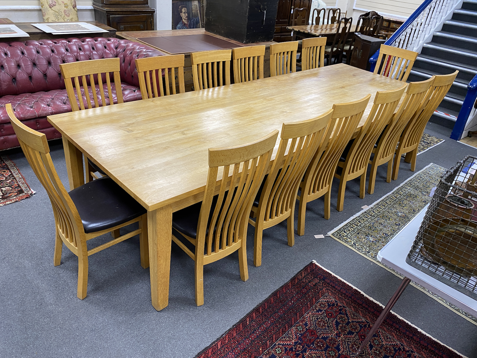 A large contemporary rectangular oak dining table, length 330cm, depth 119cm, height 76cm, and fourteen associated wavy bar back dining chairs.                                                                             