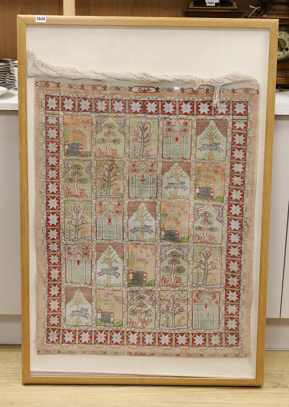 An Eastern framed silk rug depicting trees amimals and buildings, 86 cms high x 67cms wide                                                                                                                                  