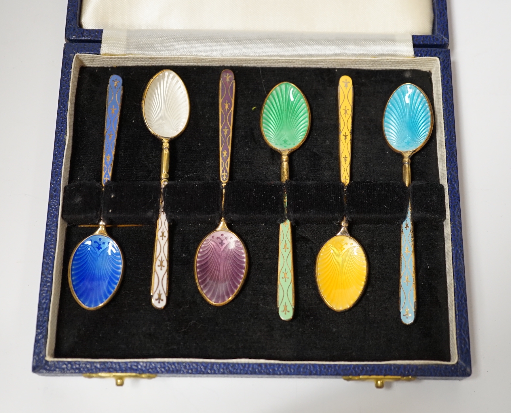 A cased set of six Elizabeth II silver gilt and polychrome enamelled coffee spoons, Turner & Simpson, Birmingham, 1968, 93mm.                                                                                               