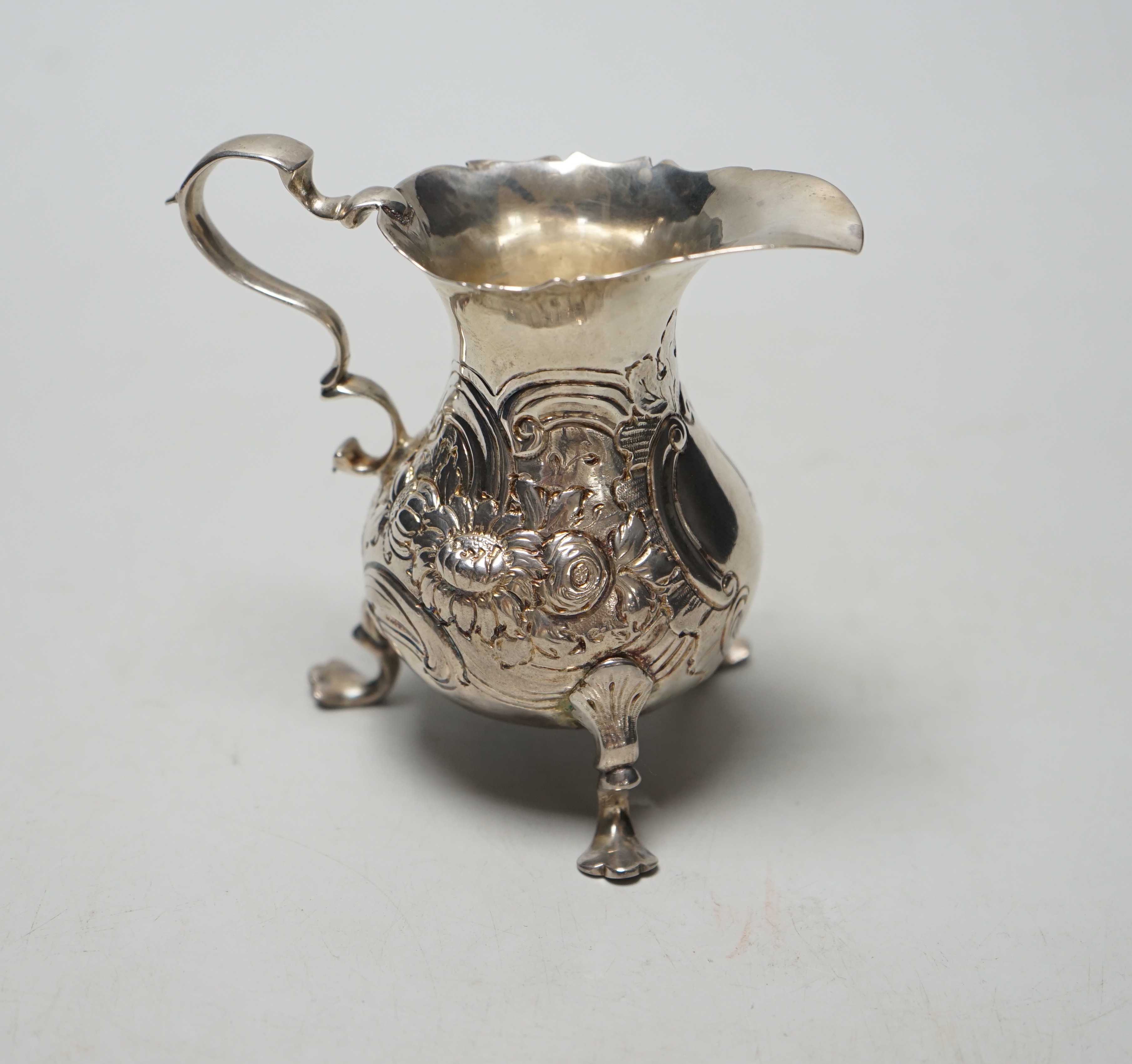 A George II silver cream jug, with later embossed decoration, marks rubbed, London, 1750? (a.f.), height 89mm, 77 grams.                                                                                                    