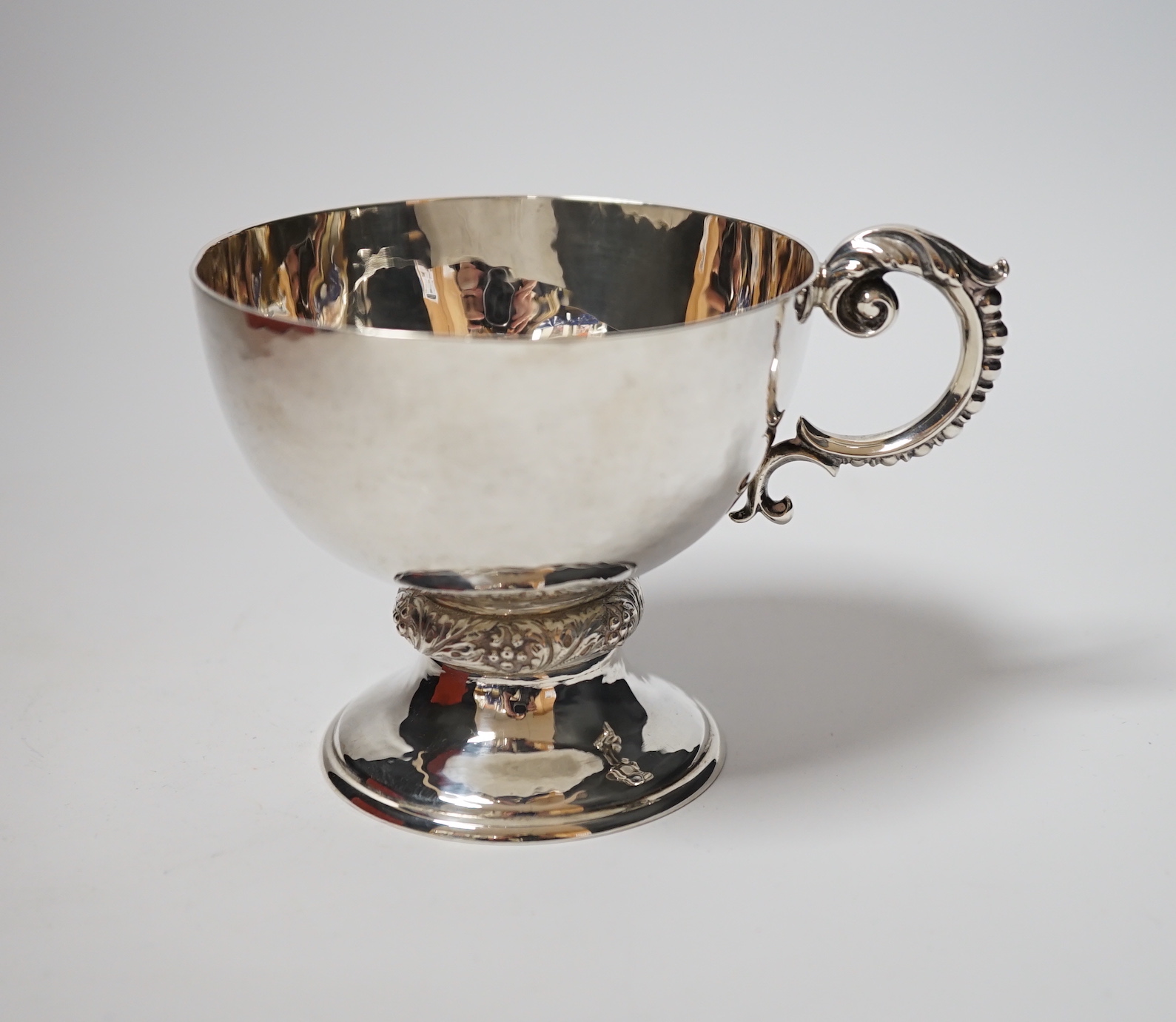 A George V planished silver pedestal single handled cup, Goldsmiths & Silversmiths Co Ltd, London, 1926, 86mm, 5.9oz.                                                                                                       