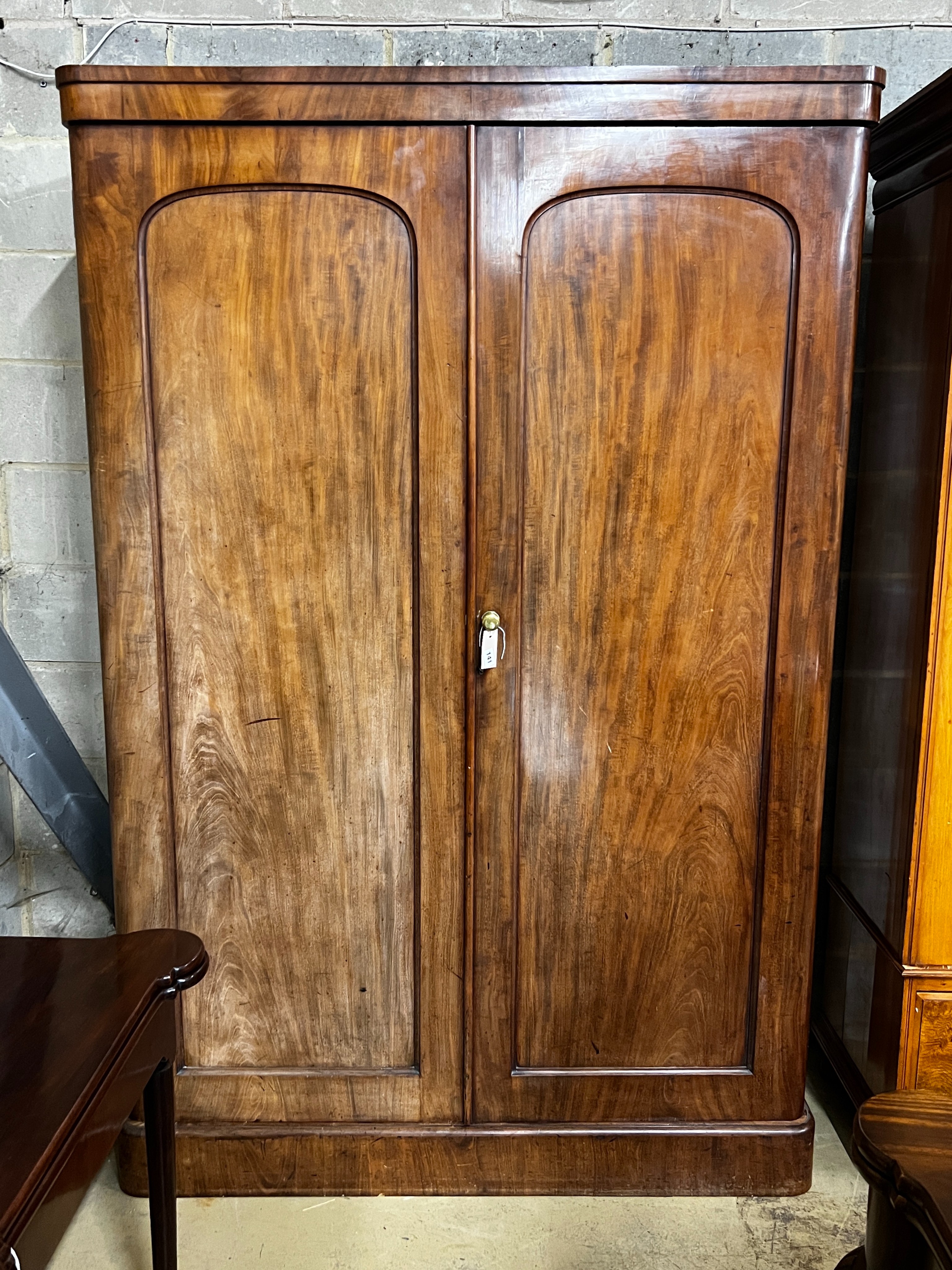 A Victorian mahogany wardrobe, enclosed by a pair of arched panelled full length doors, width 132cm, depth 55cm, height 203cm                                                                                               
