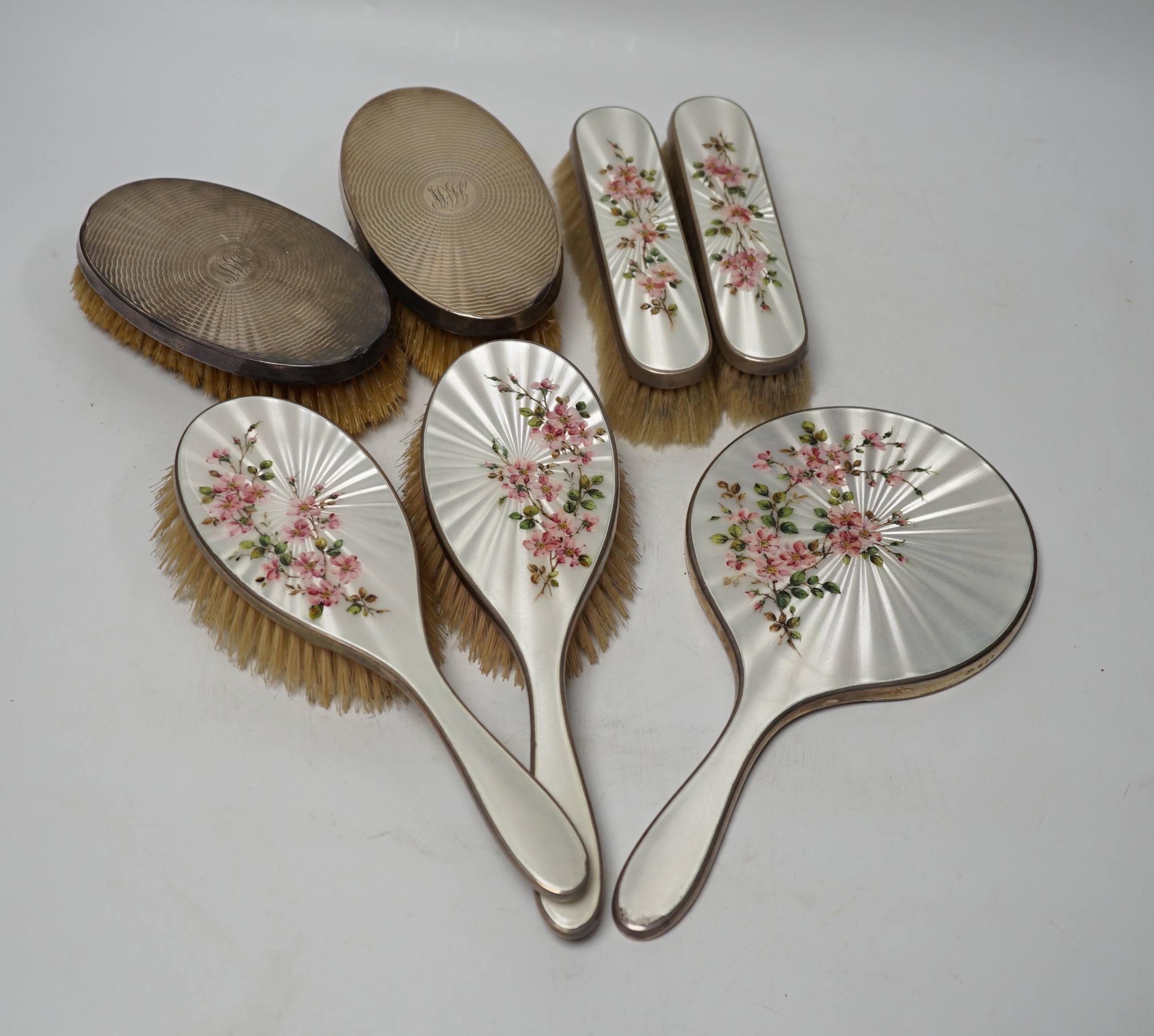 A George VI five piece silver and enamel mounted mirror and brush set, London, 1941 and a pair of silver mounted clothes brushes.                                                                                           